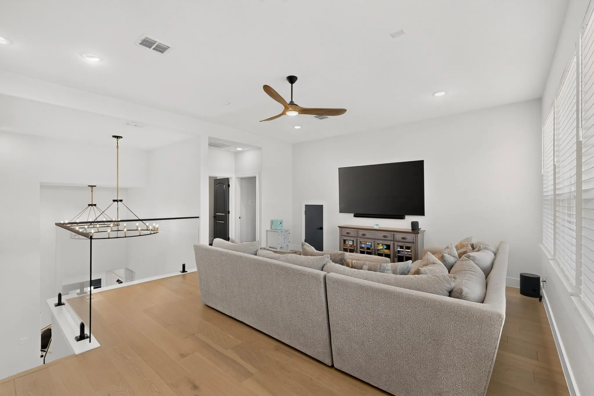 Expansive upper-level living space with wood-finish flooring, recessed lighting, and a modern ceiling fan