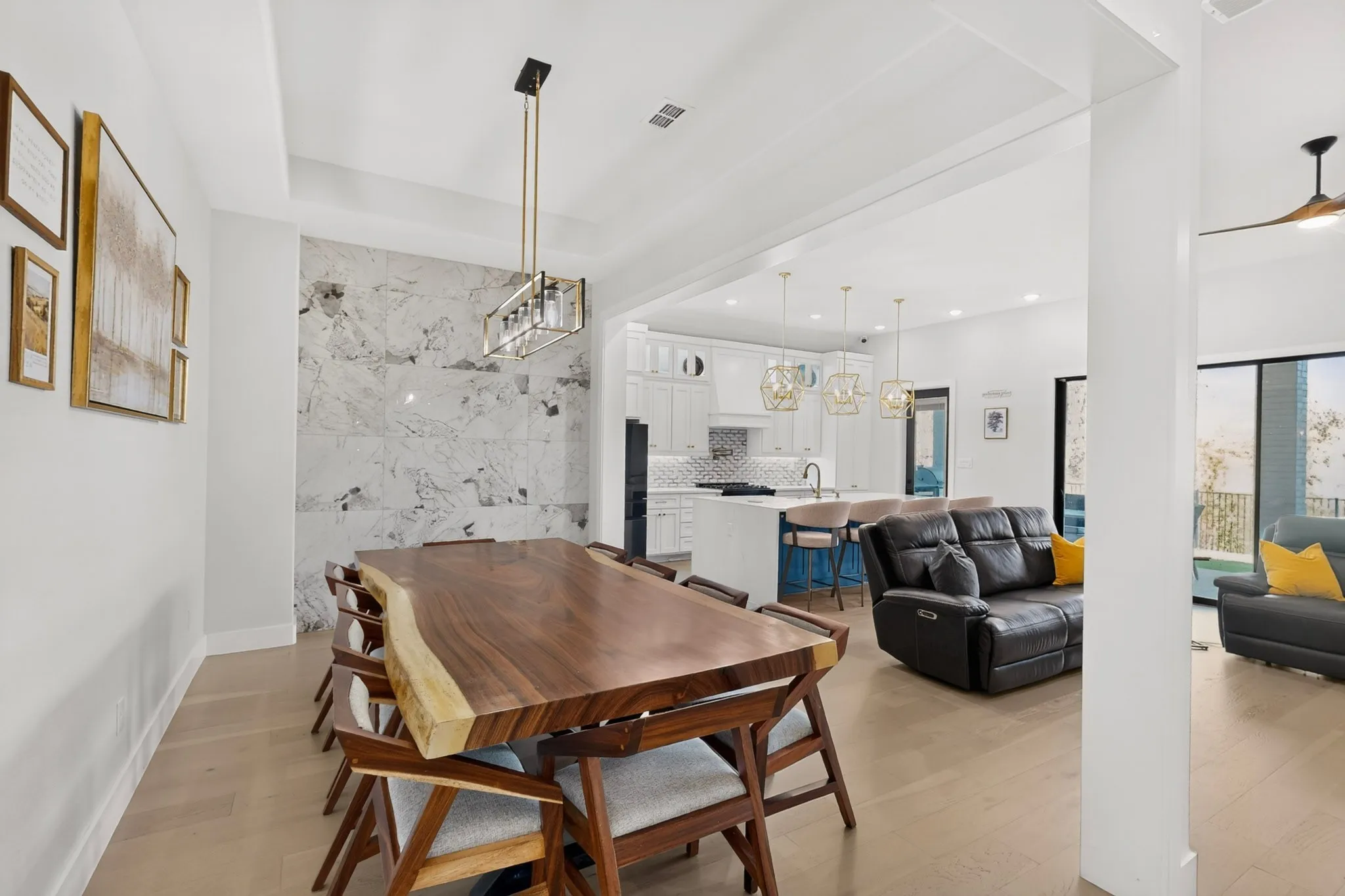 Open concept living space featuring light wood-finish flooring, a tray ceiling, and a prominent stone accent wall