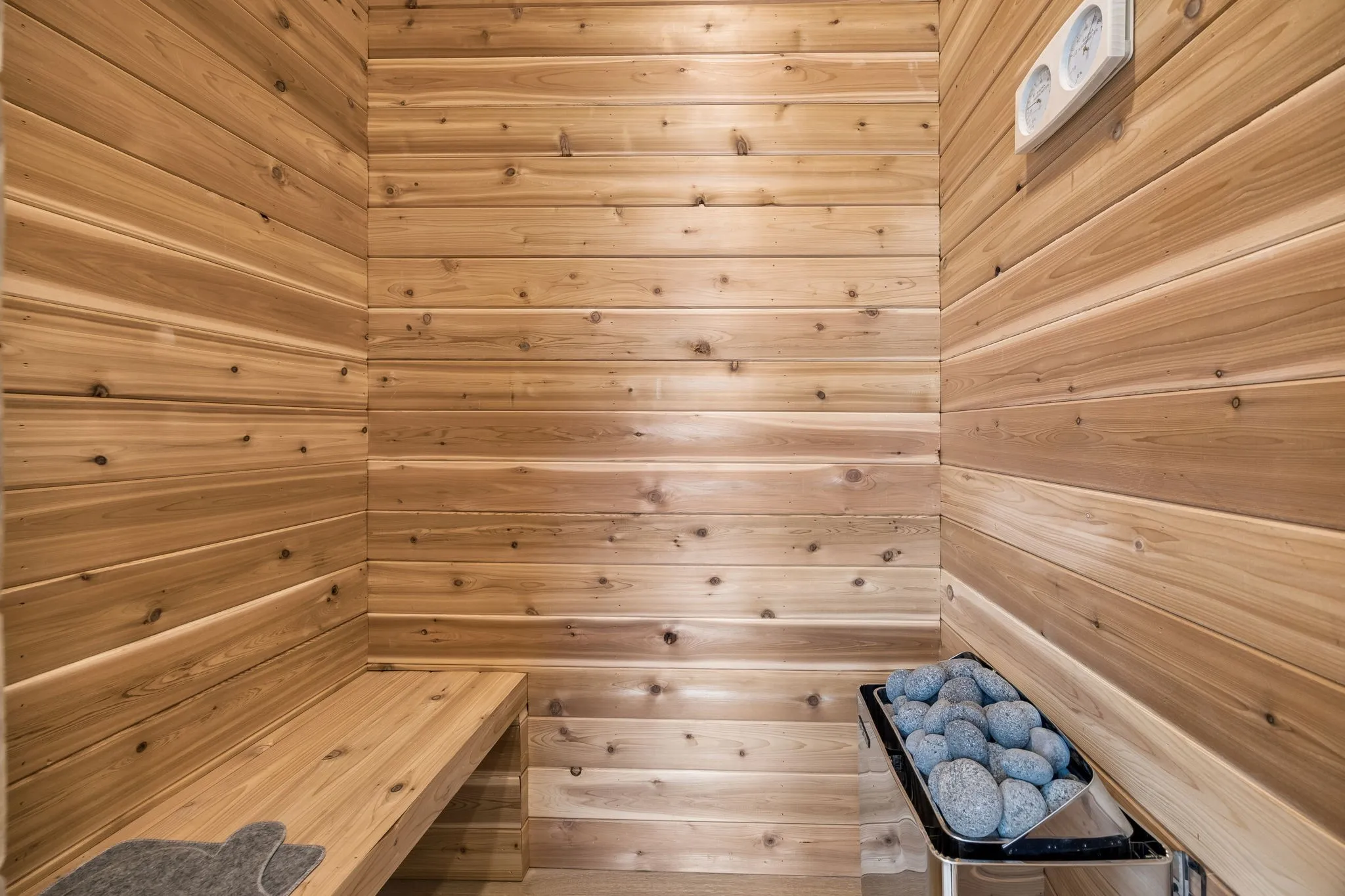 Wood paneling, built-in wooden bench, integrated heater with stones, wall-mounted control panel