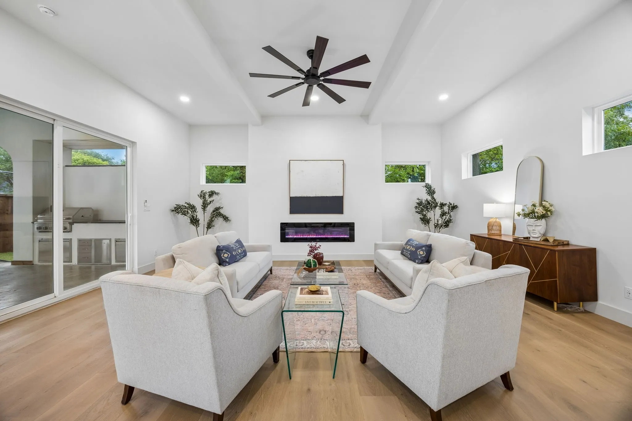 Expansive living area with high ceilings, an electric fireplace and a ceiling fan