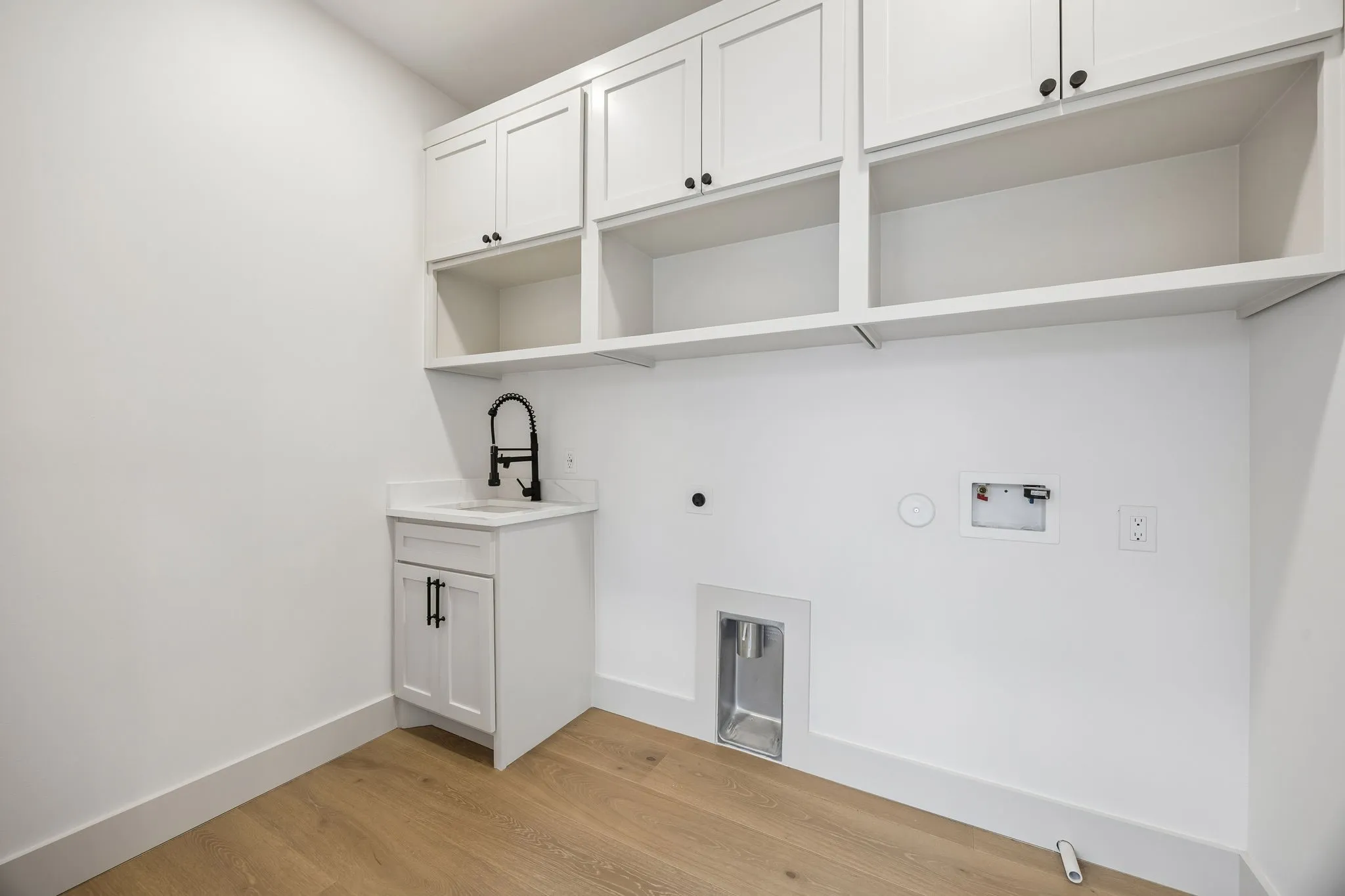 Laundry room with open and closed storage and a sink.