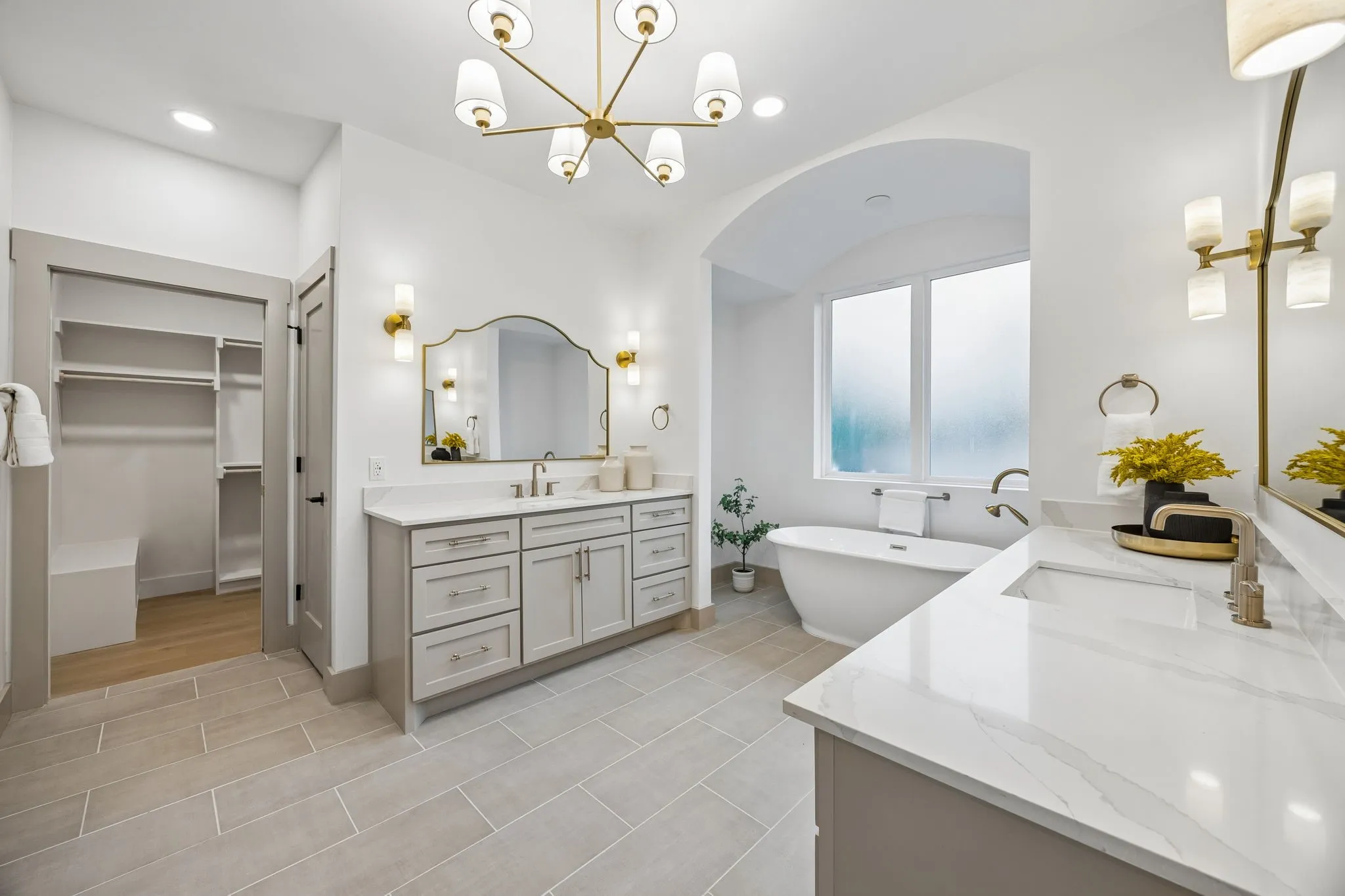 Spacious ensuite bathroom featuring a freestanding tub, dual vanities and a walk-in closet with built-in shelving