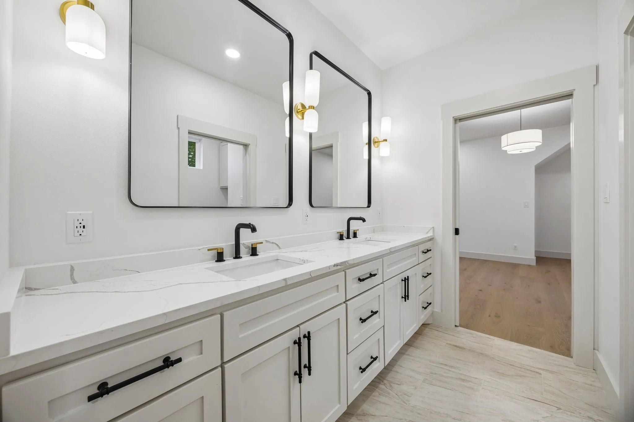 Dual vanity with white cabinetry, matte black hardware, integrated sinks, and polished countertops