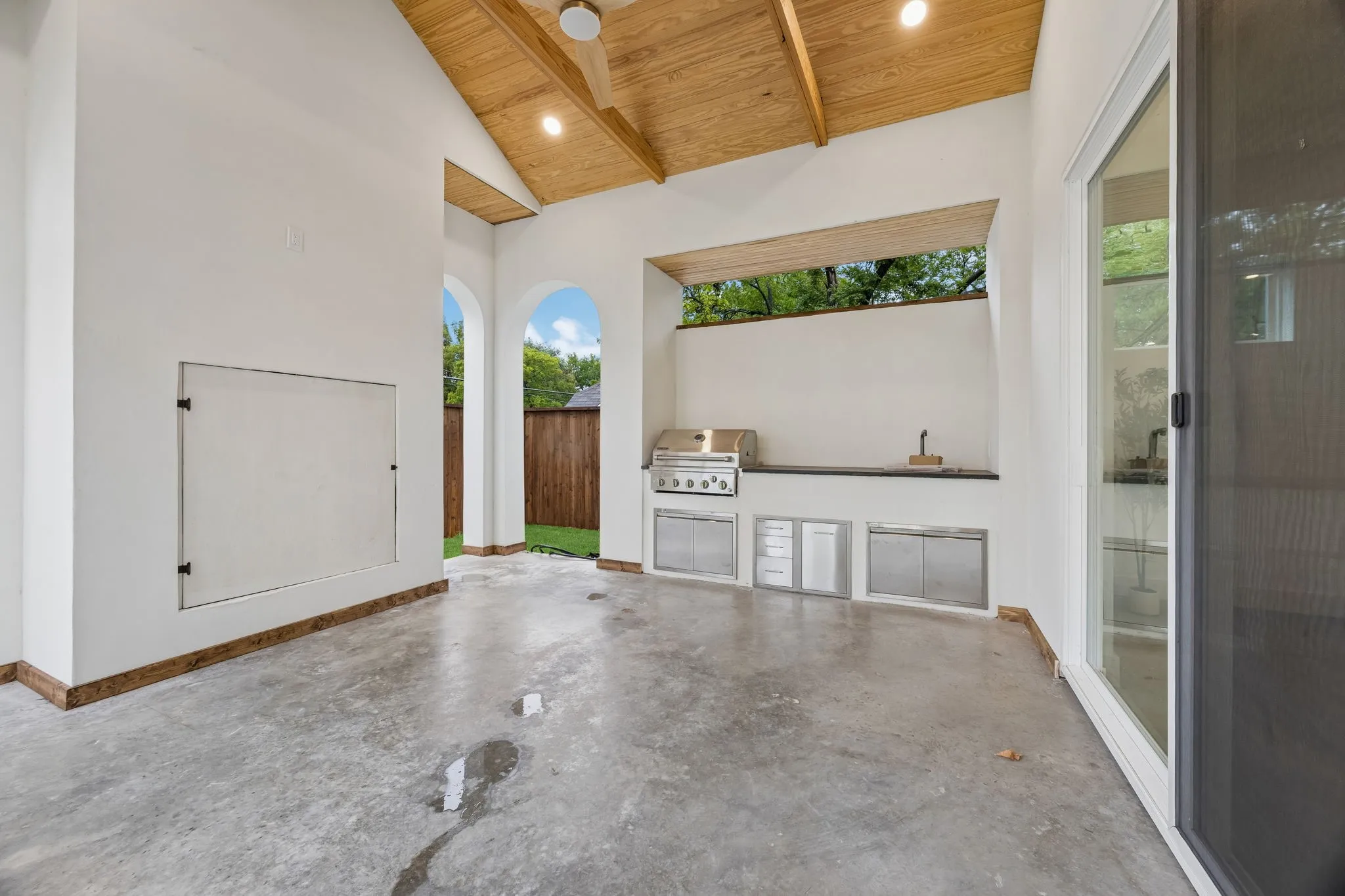 Covered back patio with exposed beams, integrated outdoor kitchen with stainless steel appliances