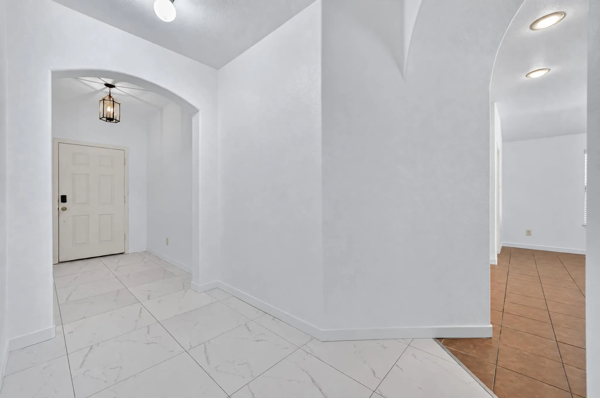 Entryway featuring white square tile flooring, archway, and a dark bronze hanging lantern fixture