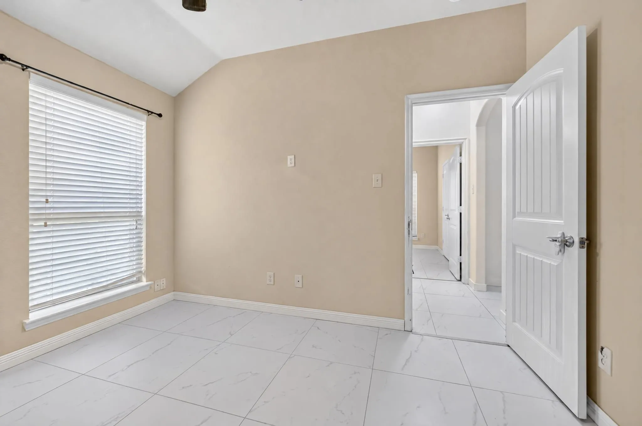 Vaulted ceiling, white tiled flooring, arched doorway, panel doors, and window with blinds