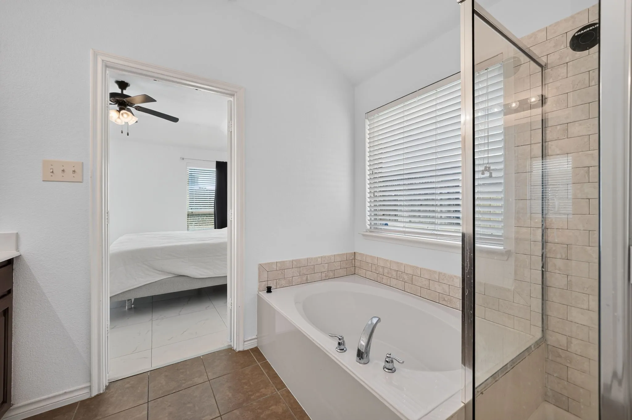 Built-in soaking tub with chrome fixtures, tiled surround, and separate glass-enclosed shower featuring subway tile