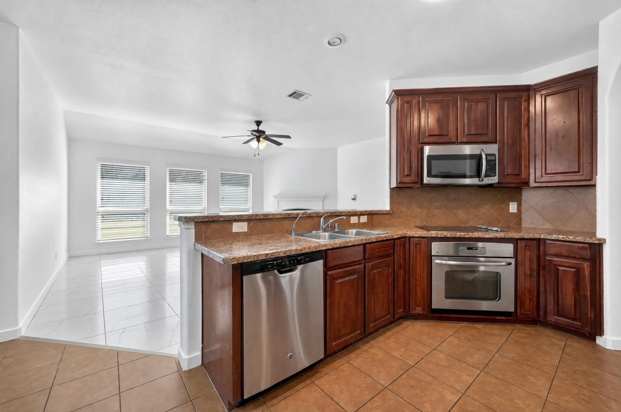 Kitchen featuring dark wood-finish cabinetry, stainless steel appliances, and a tiled backsplash