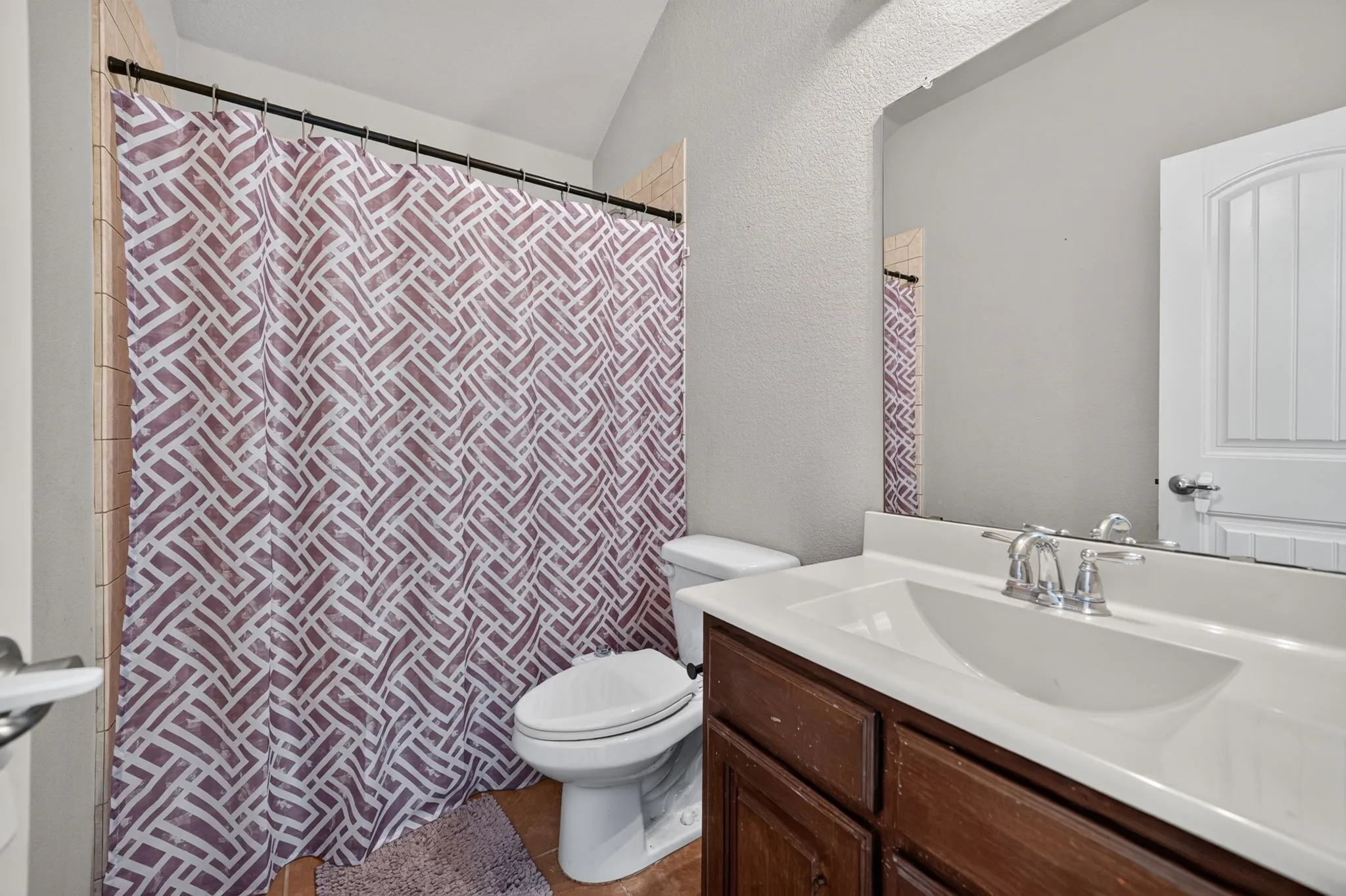 Bathroom featuring a dark wood-finish vanity, integrated sink, chrome faucet, and a large wall mirror