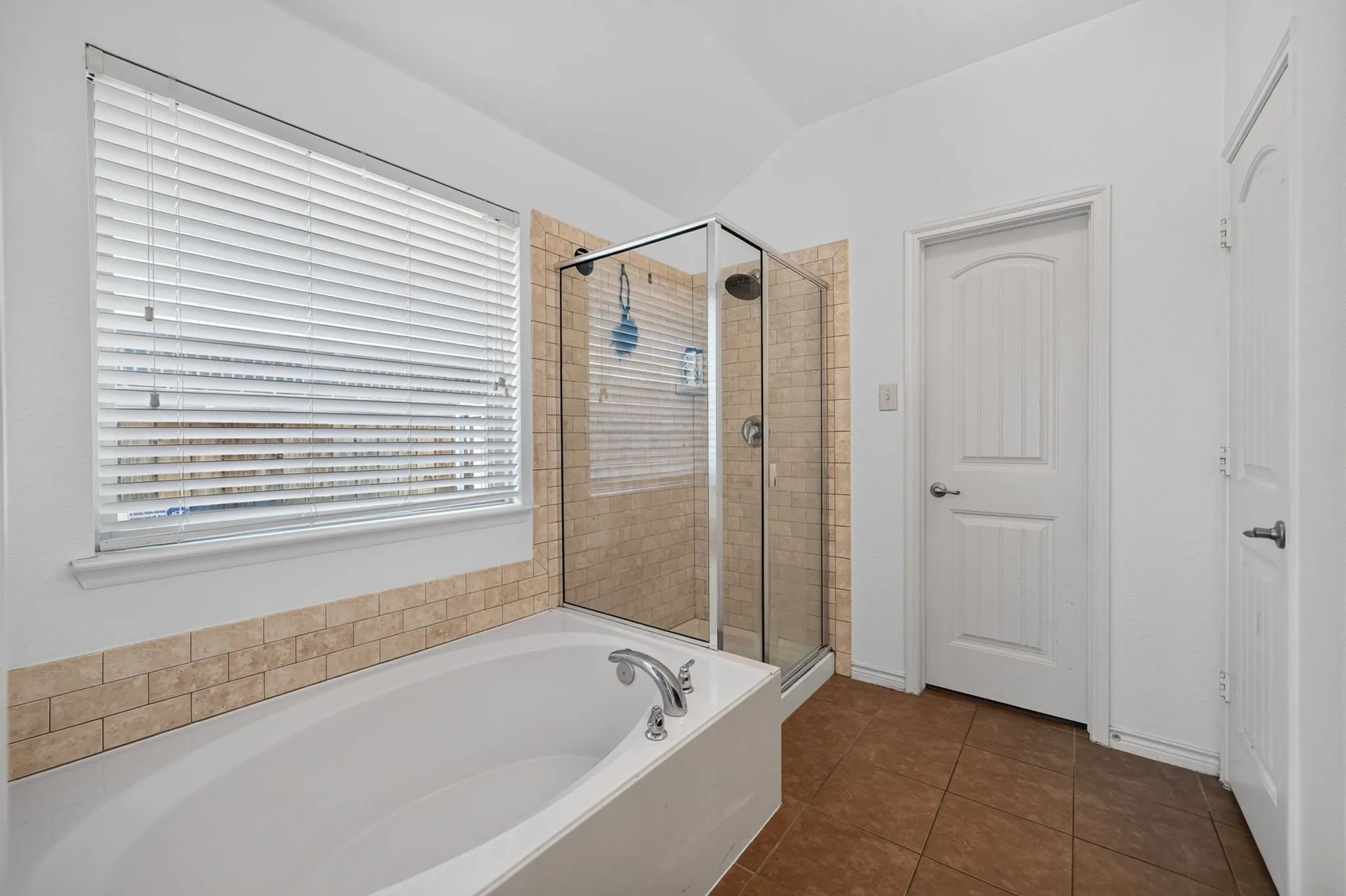 Soaking tub with chrome fixtures, glass-enclosed shower, and subway tile surround
