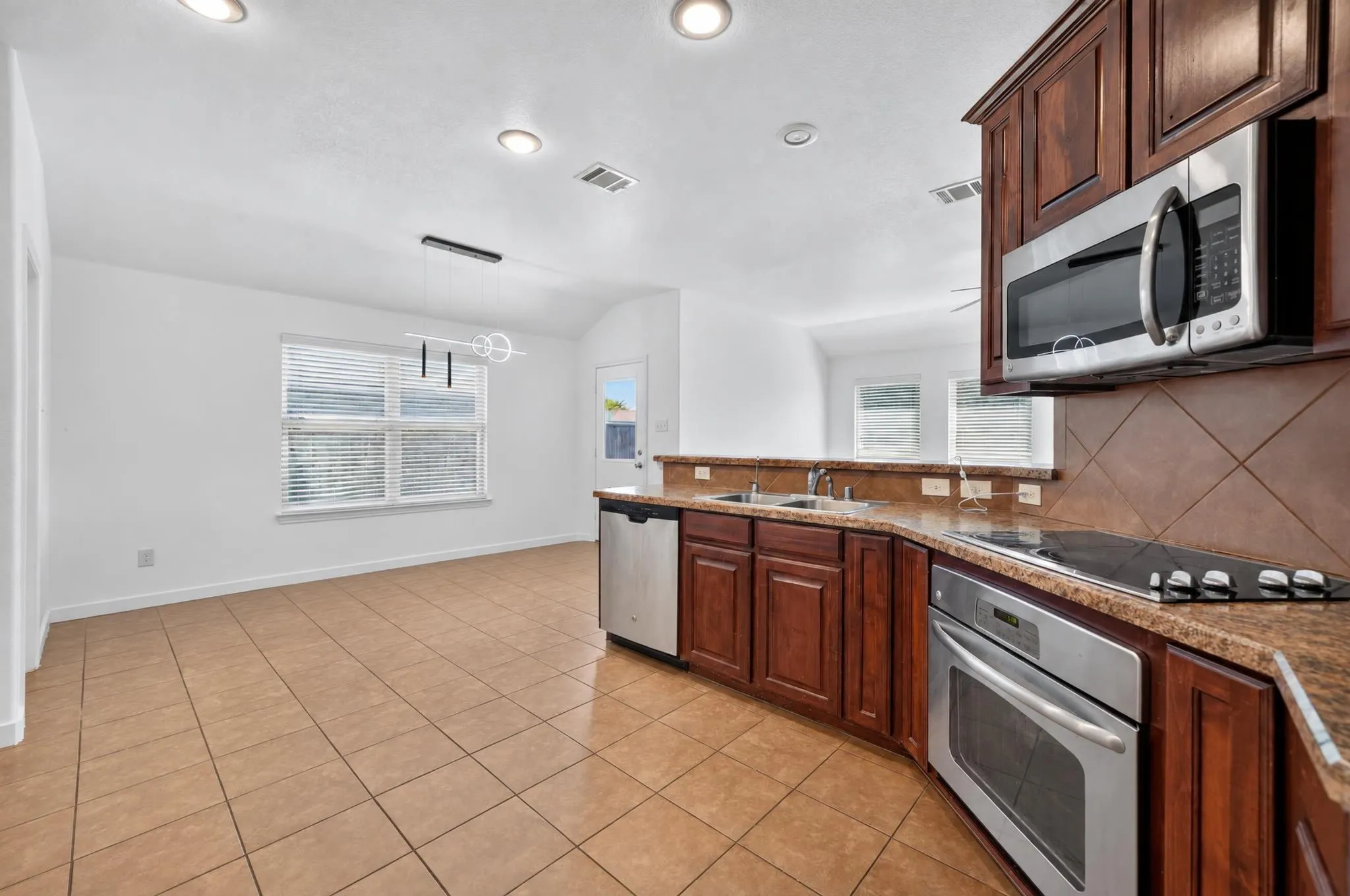 Kitchen with wood-finish cabinetry, stainless steel appliances, and a tiled backsplash