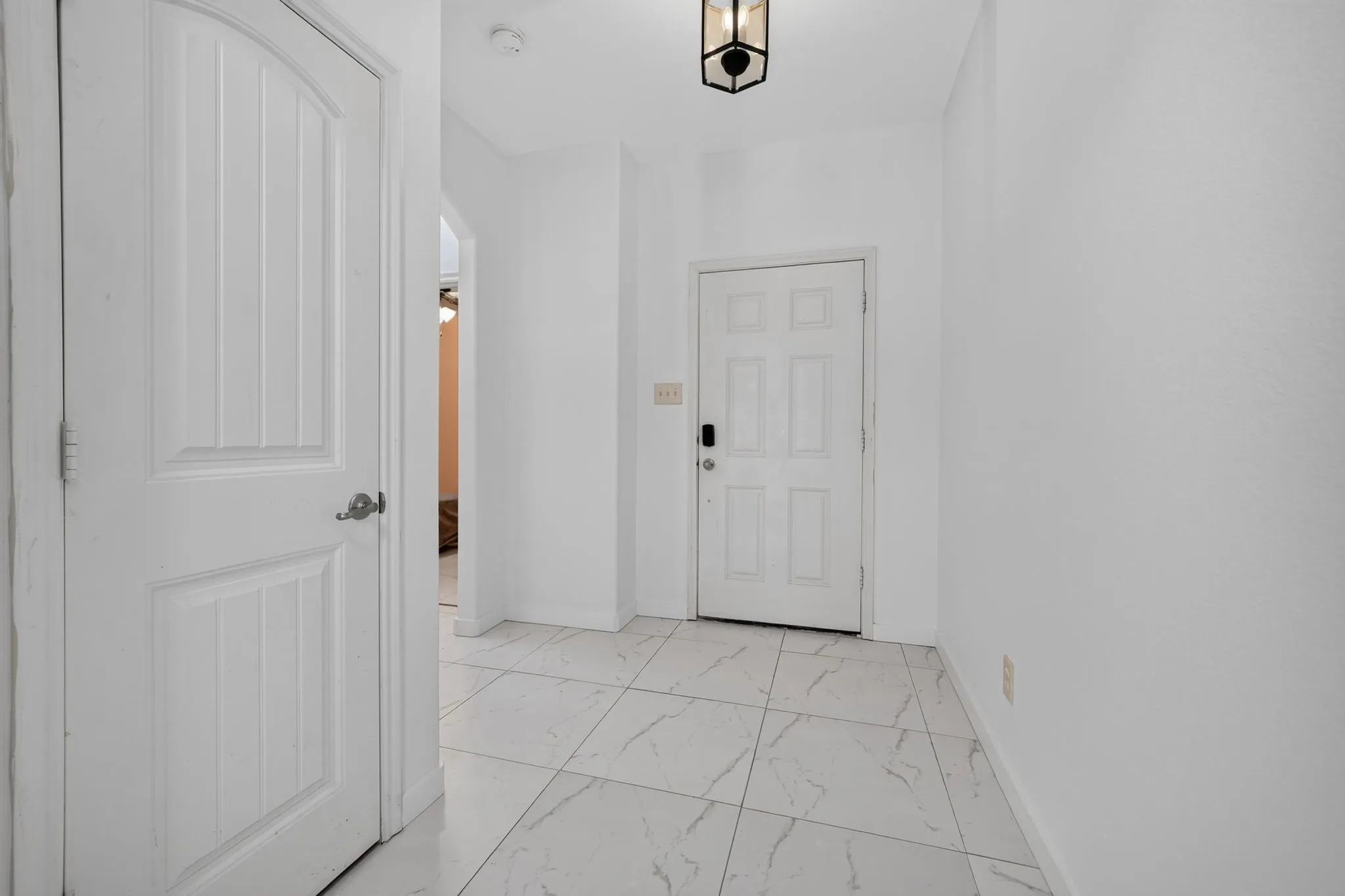 Spacious entryway with large format floor tile, recessed lighting, and a modern pendant light fixture