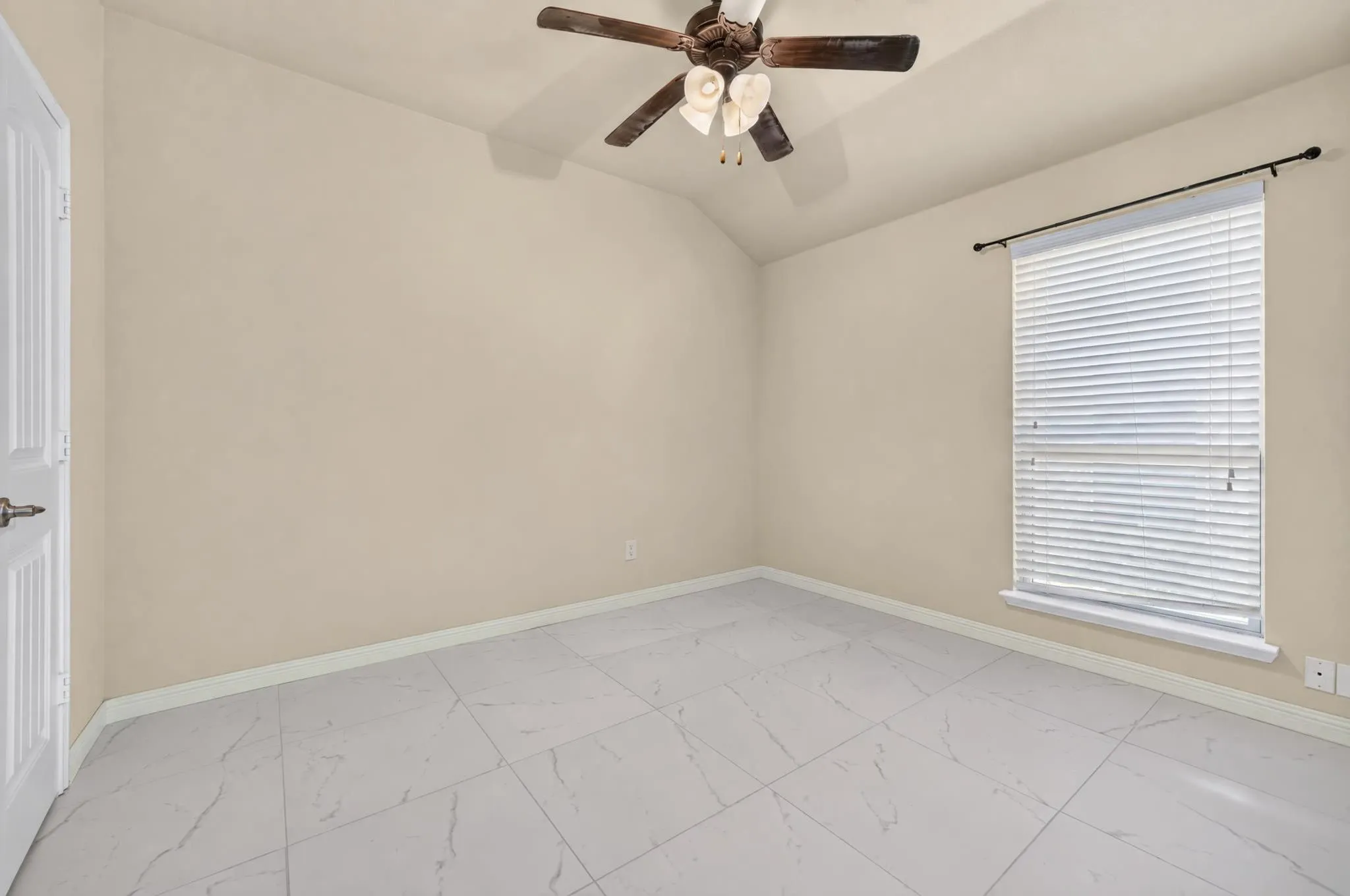 Varying ceiling height with a ceiling fan, window with blinds, light-toned walls, and large format tile flooring