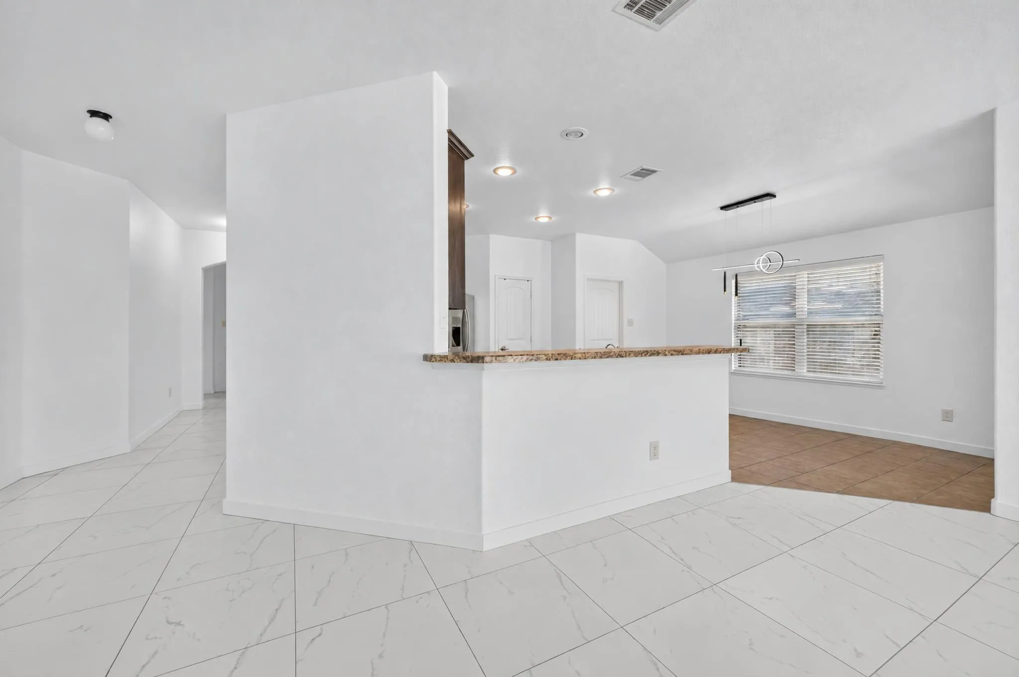 White tile flooring, breakfast bar with a stone counter, recessed lighting, and a window with blinds