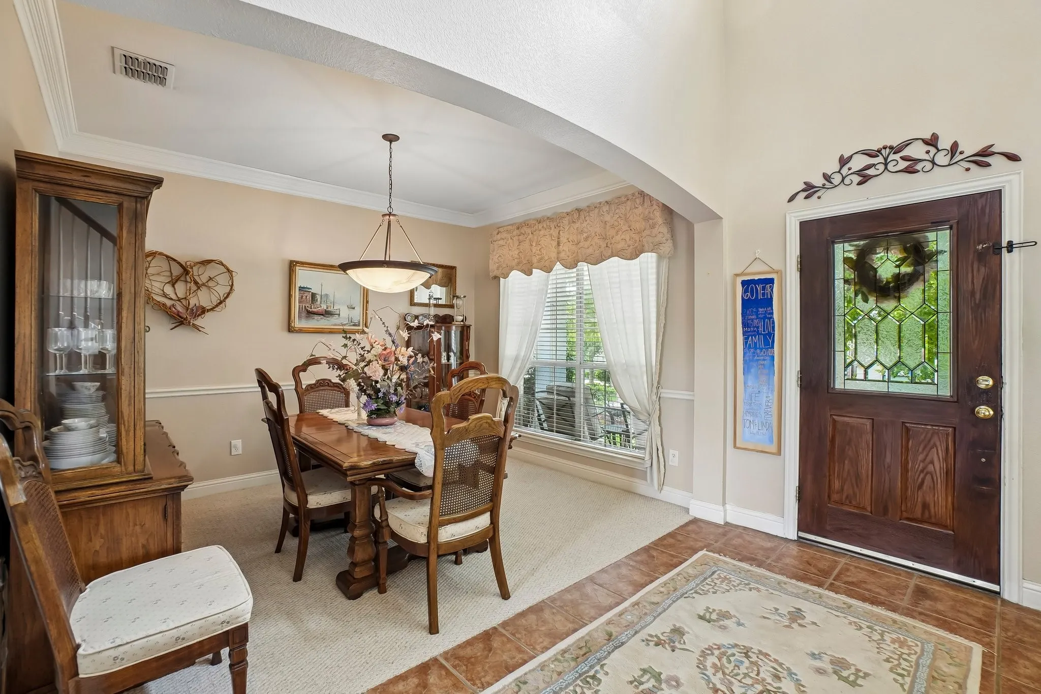 Arched entryway opening to a dining area with tray ceiling and chandelier