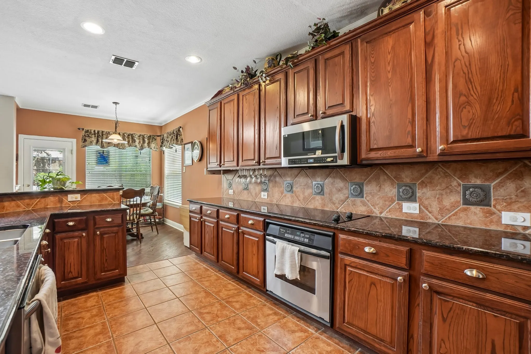 Wood-finish cabinetry paired with dark countertops and a tile backsplash