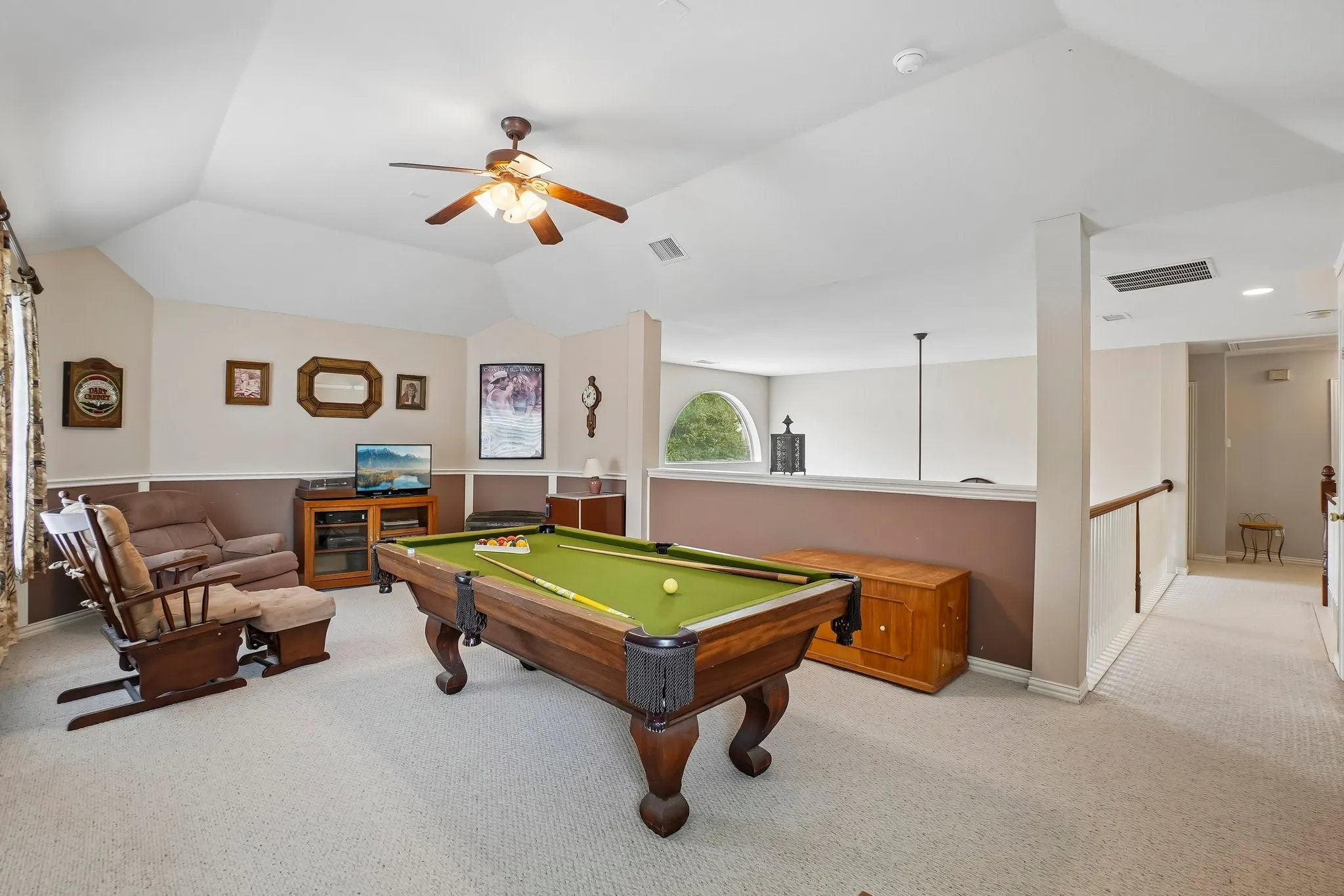 Vaulted ceilings, ceiling fan, carpeted flooring, arched window, and wood handrail