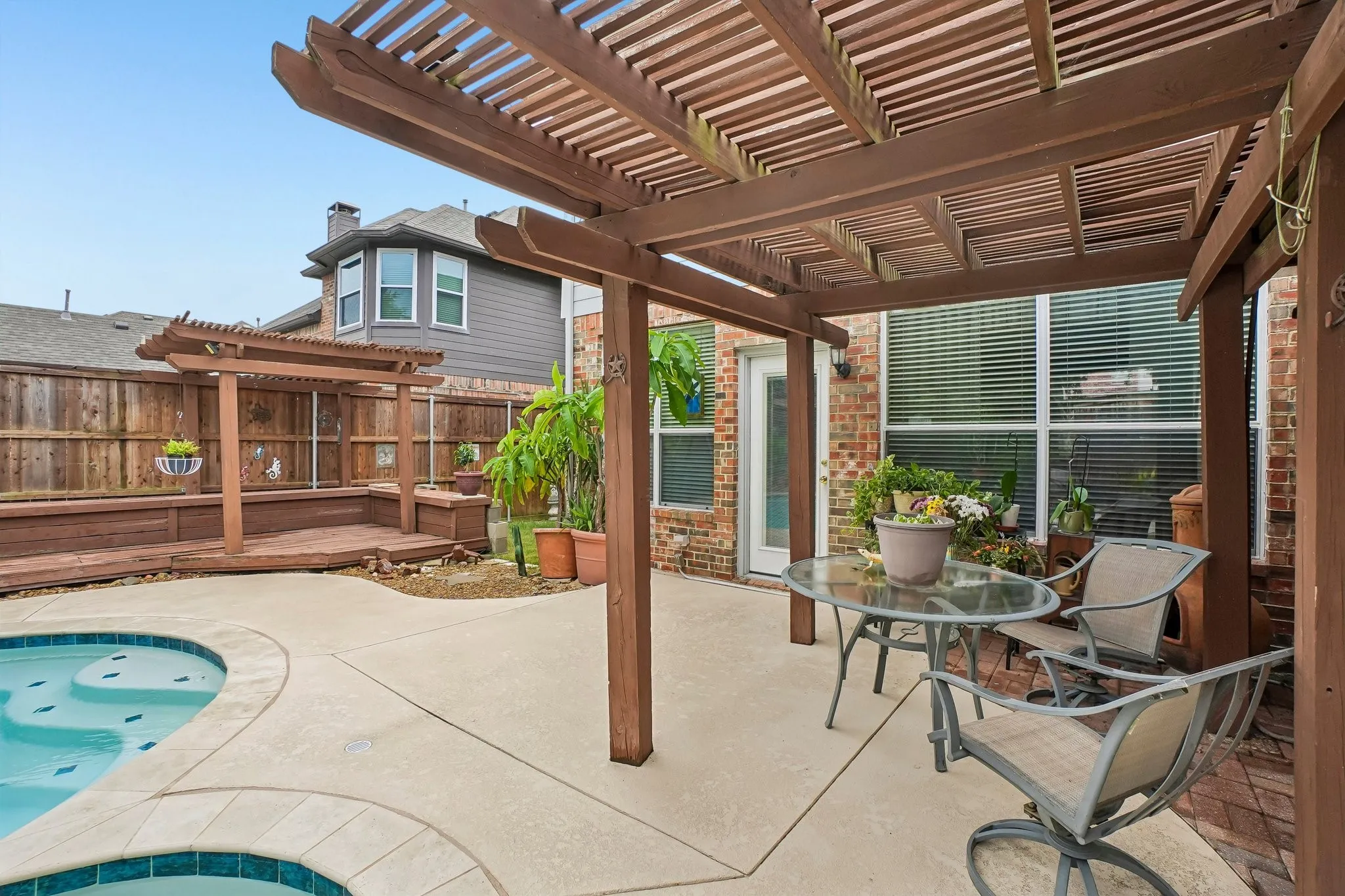 Outdoor living area featuring a covered patio, an in-ground pool, a privacy fence, and a built-in wooden bench with a pergola