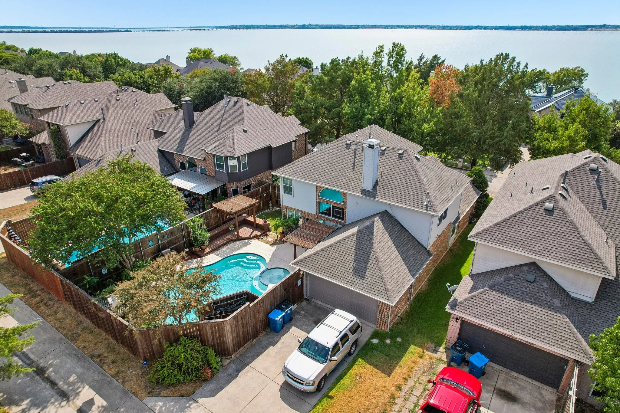 Rear exterior featuring a swimming pool, integrated spa, and a wooden privacy fence with close proximity to Lake Ray Hubbard
