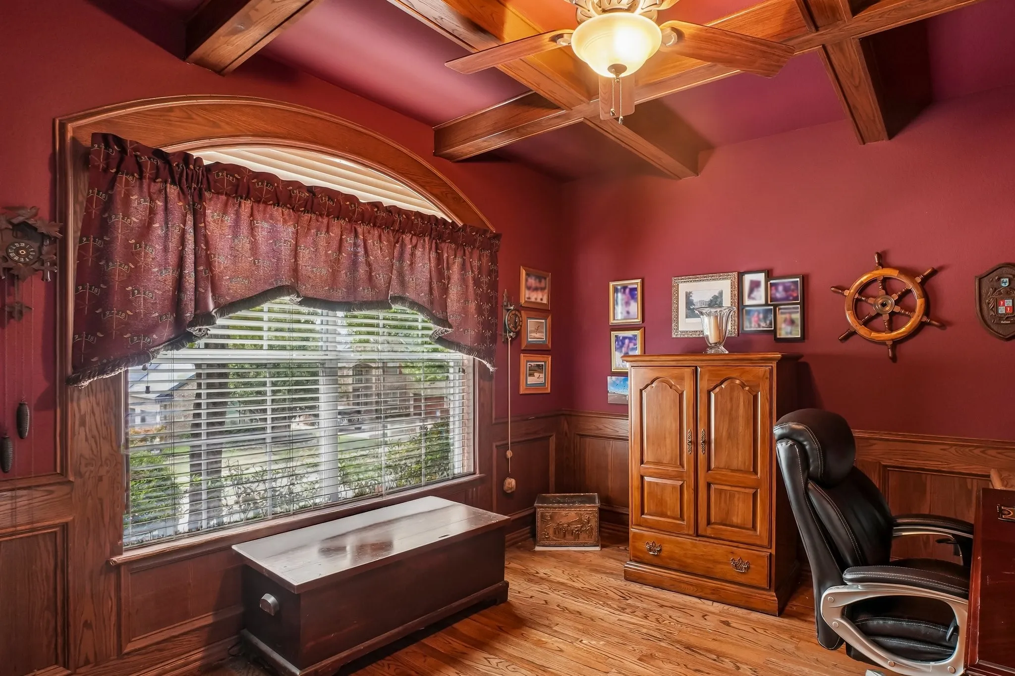 Wood-finish flooring, wood wall paneling, and a wood-beamed ceiling with a ceiling fan
