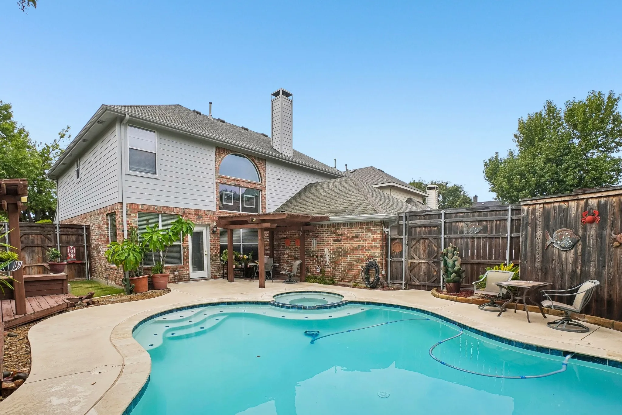 Backyard oasis featuring a swimming pool with integrated spa, concrete patio, and a wooden pergola