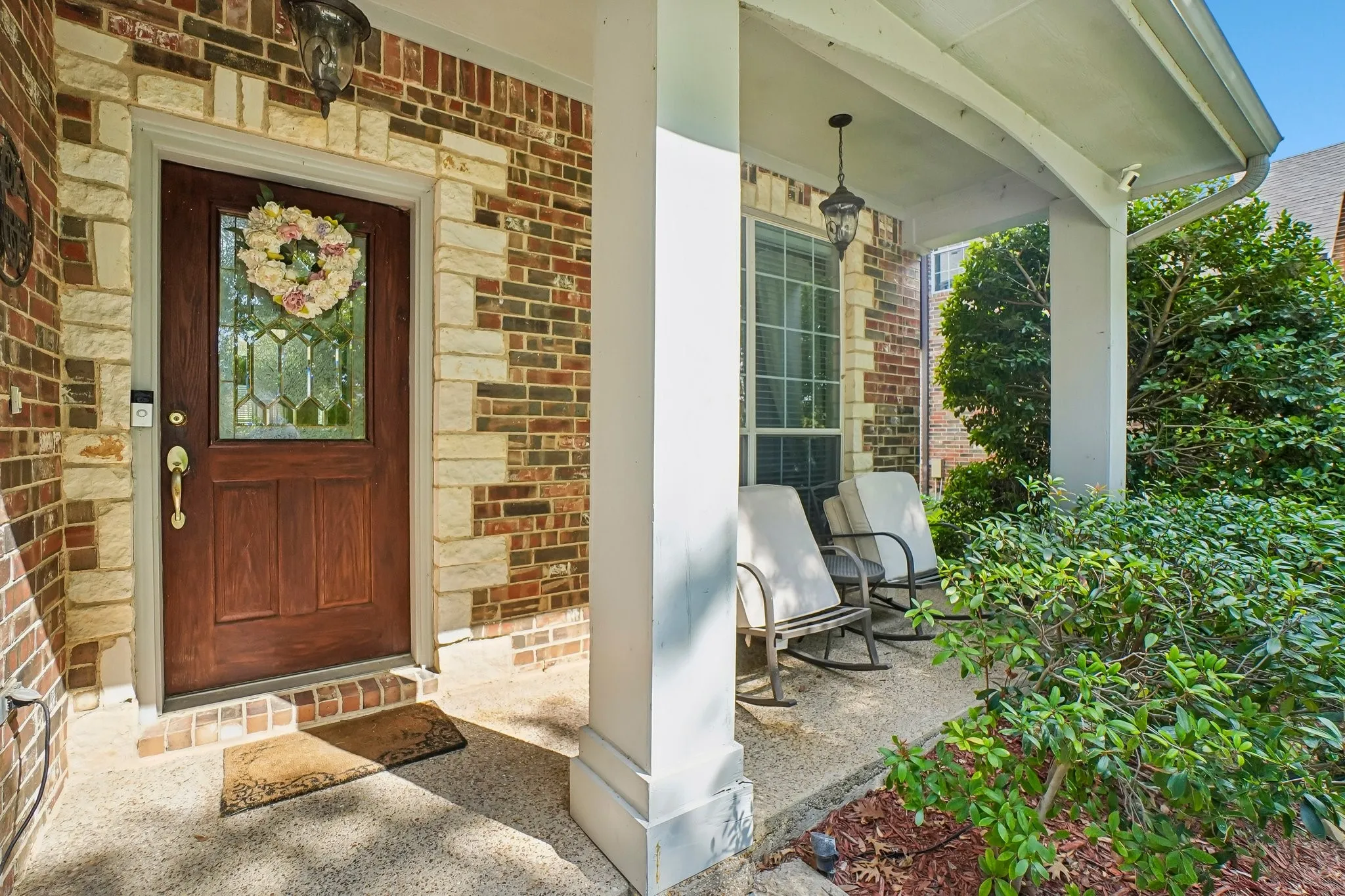 Brick and stone facade with a decorative wood entry door featuring leaded glass
