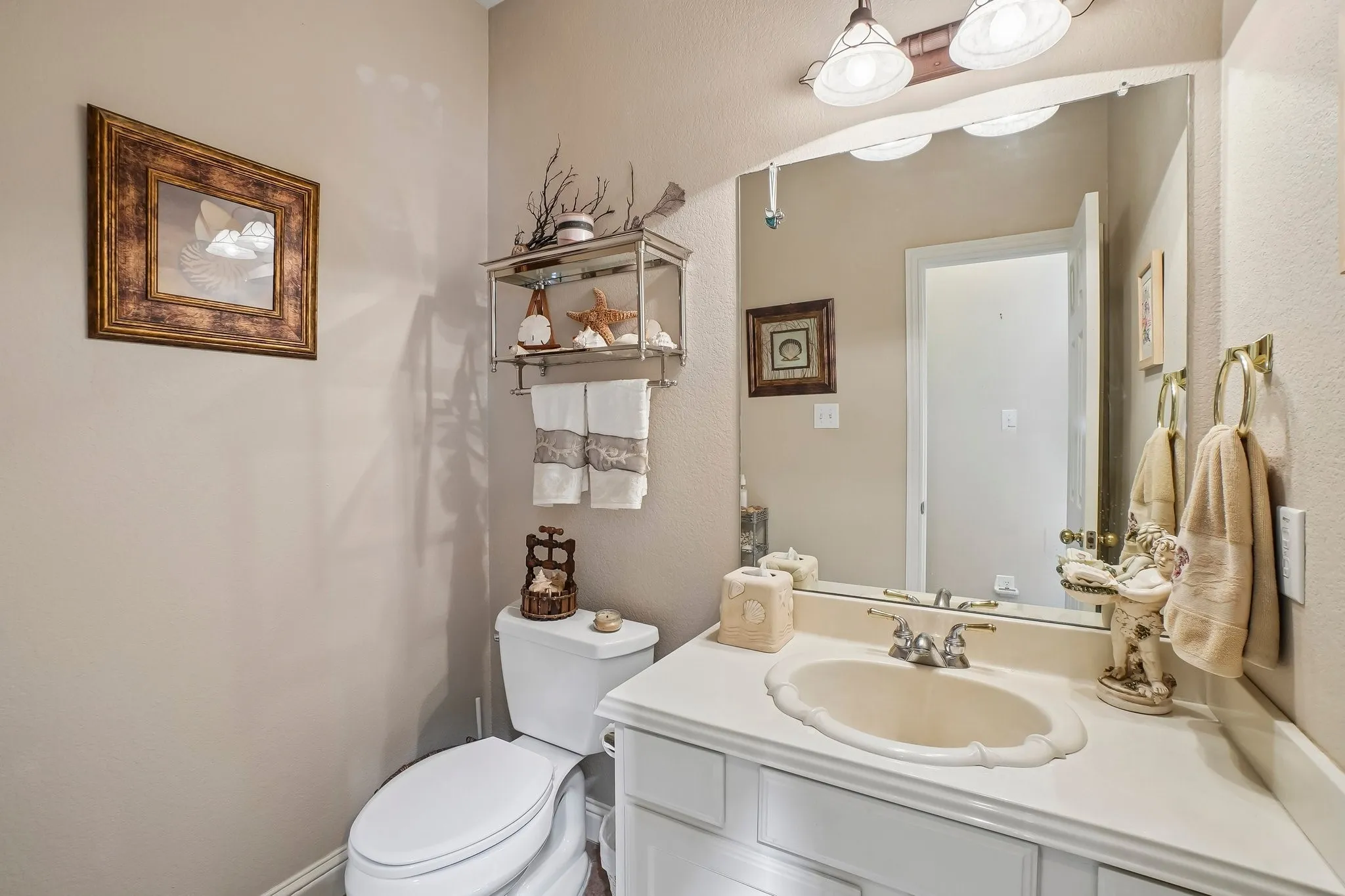 White vanity with a scalloped edge sink, dual-handle faucet, and an overhead lighting fixture