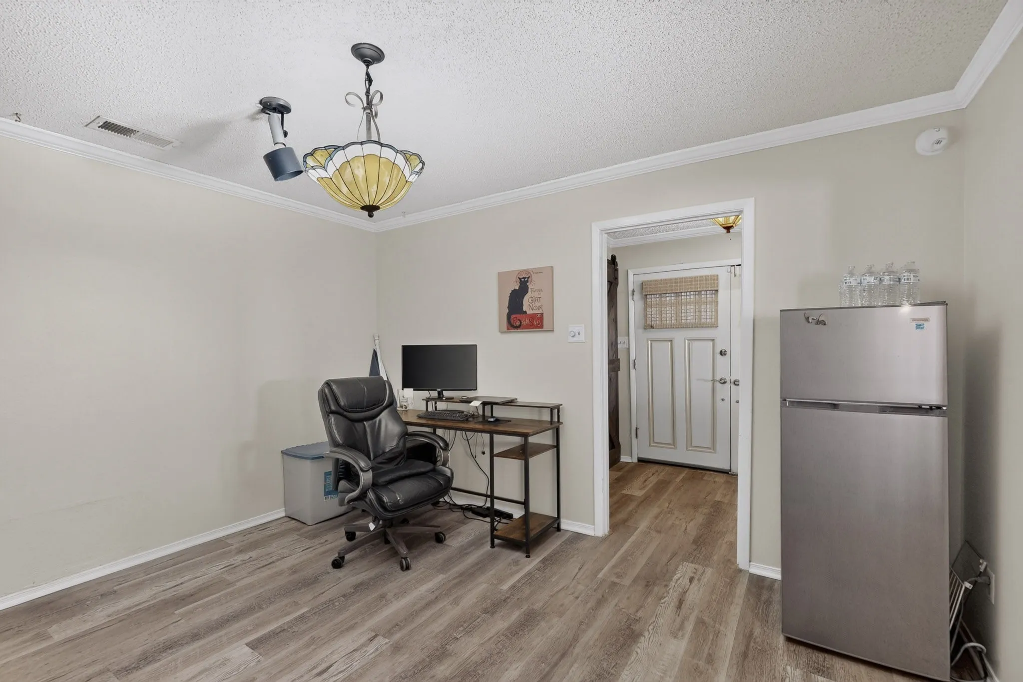 Wood-finish flooring, crown molding, and a decorative ceiling fixture