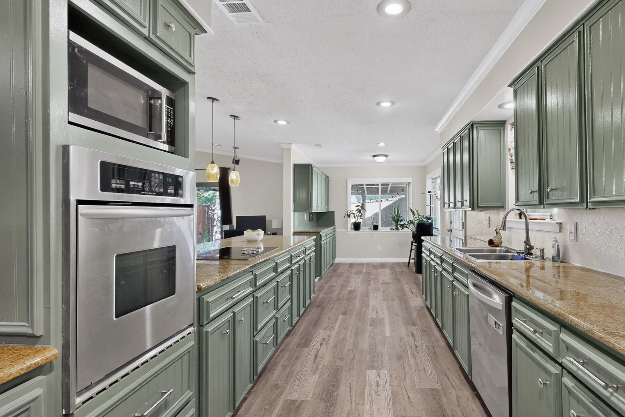 Kitchen featuring extensive cabinetry, stainless steel appliances, granite countertops, wood-finish flooring, and recessed lighting