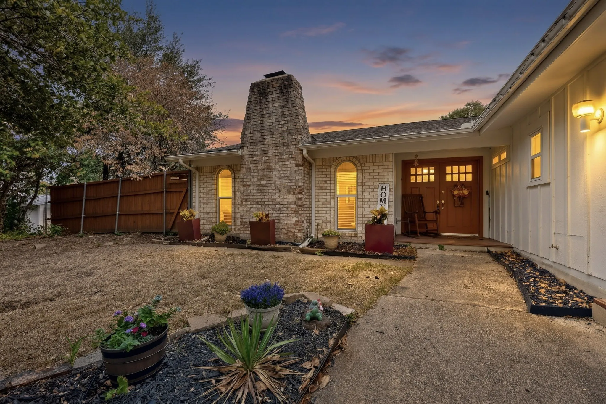 Brick exterior with a prominent chimney, arched windows, covered entry, and wood front doors