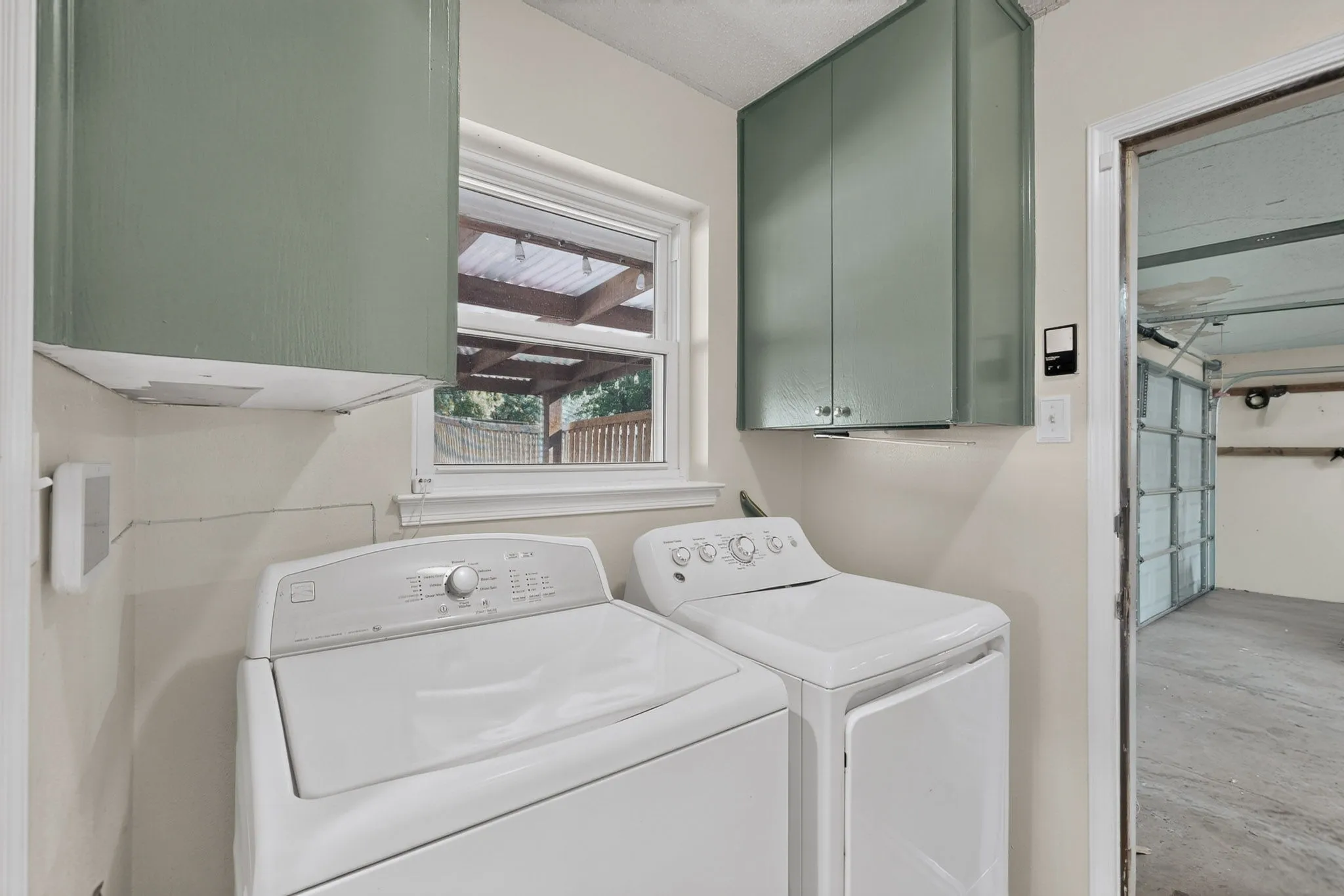 Utility area featuring light green upper cabinetry and a window with natural light