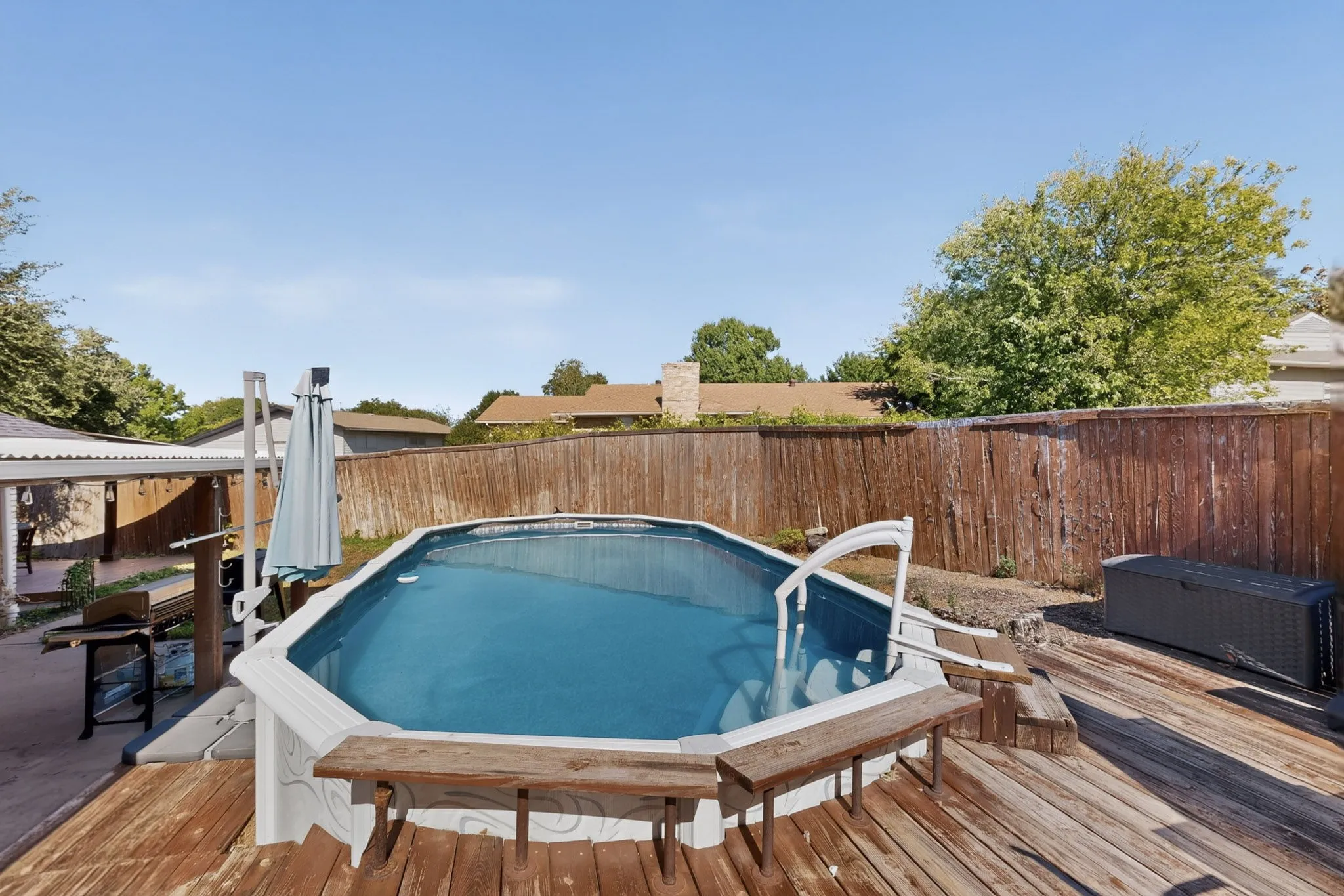 Backyard featuring an above-ground pool with a surrounding wood-finish deck and privacy fencing