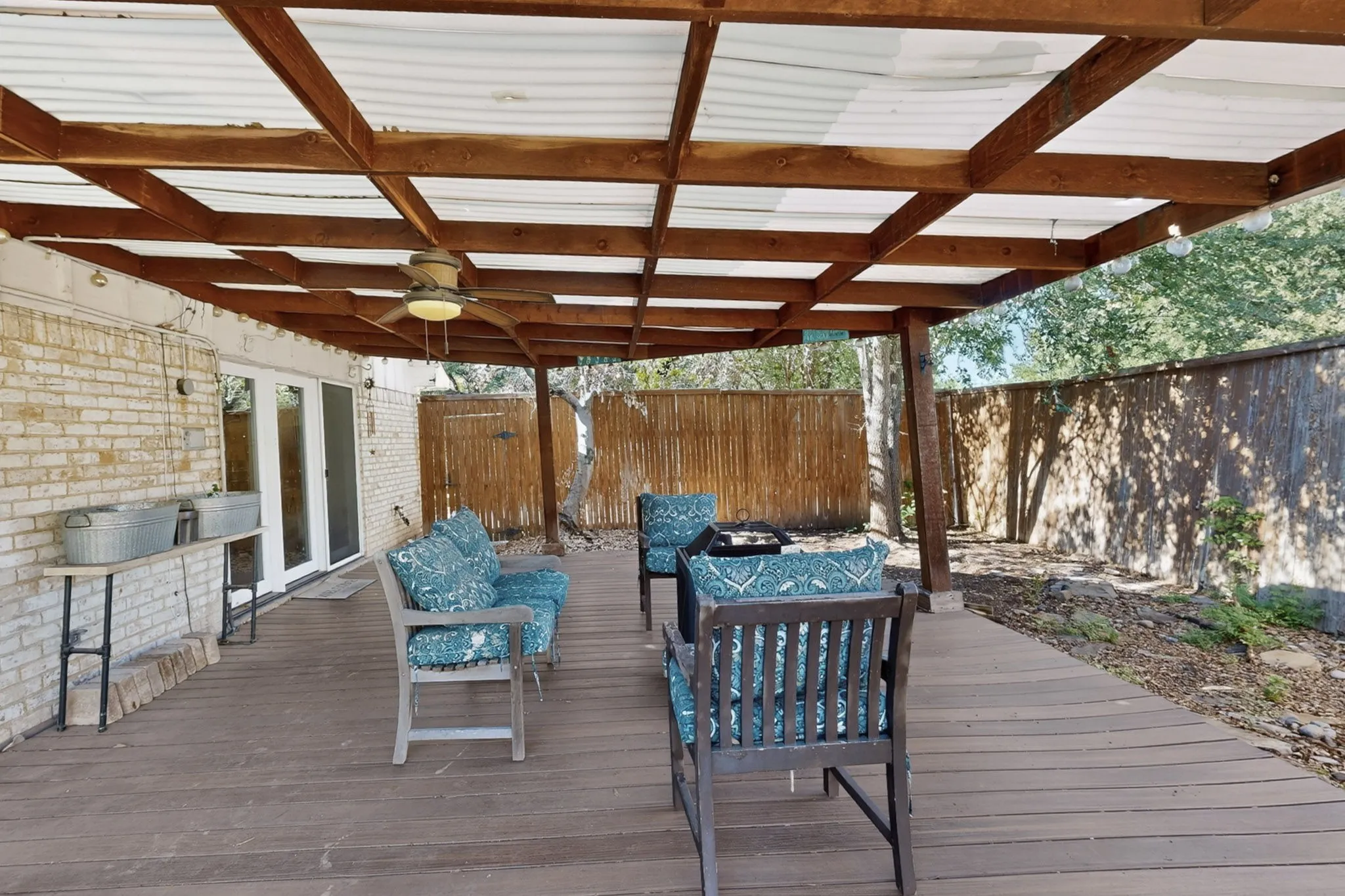 Expansive outdoor deck with wood-finish flooring, a covered pergola, and a ceiling fan