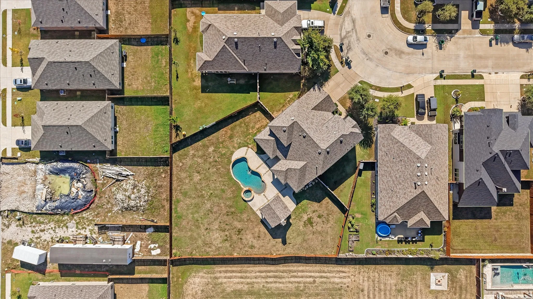 Fenced backyard with an in-ground swimming pool and adjacent hot tub