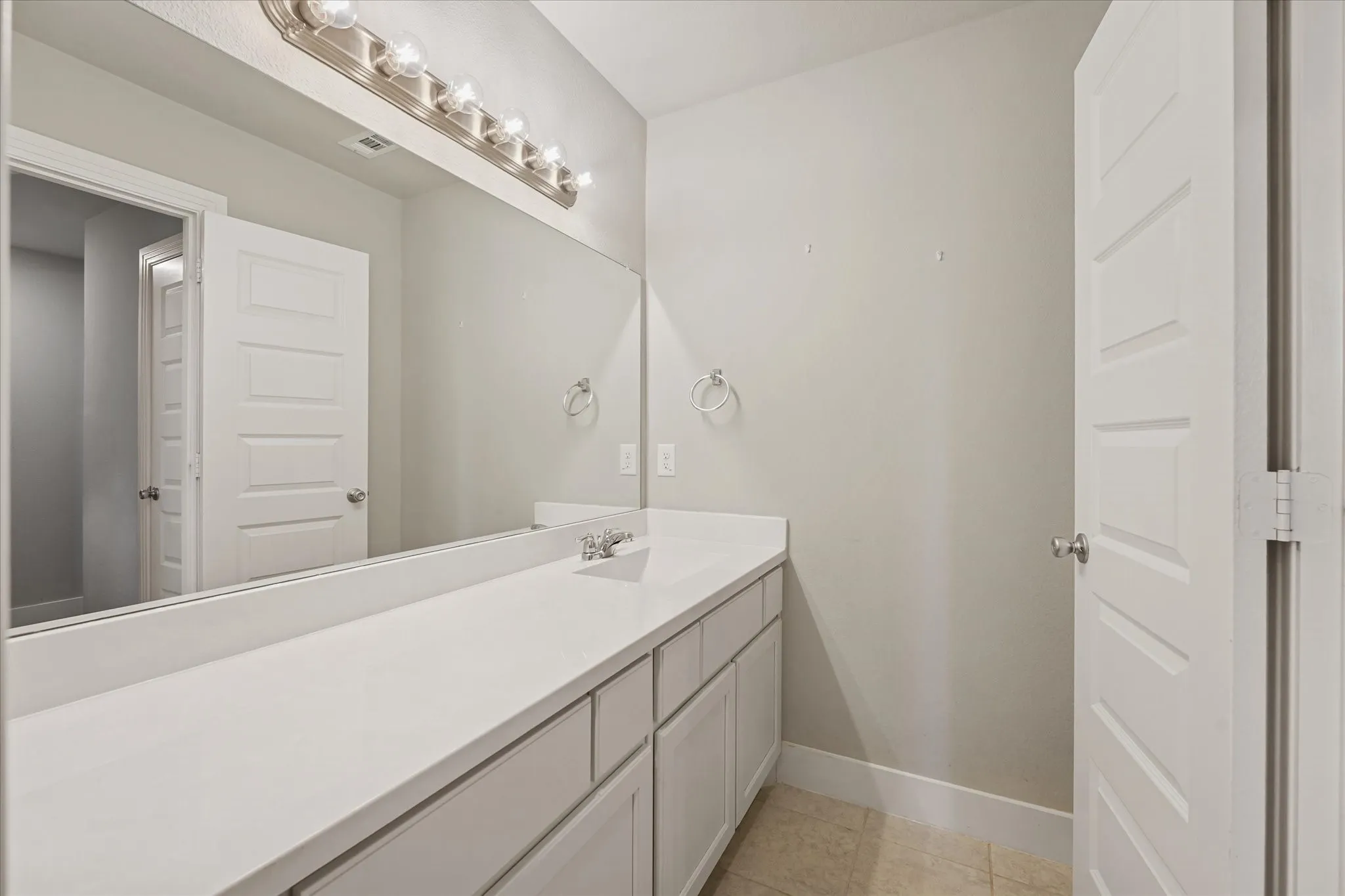Long vanity with a white countertop and integrated sink, under-cabinet storage, and a large wall-mounted mirror