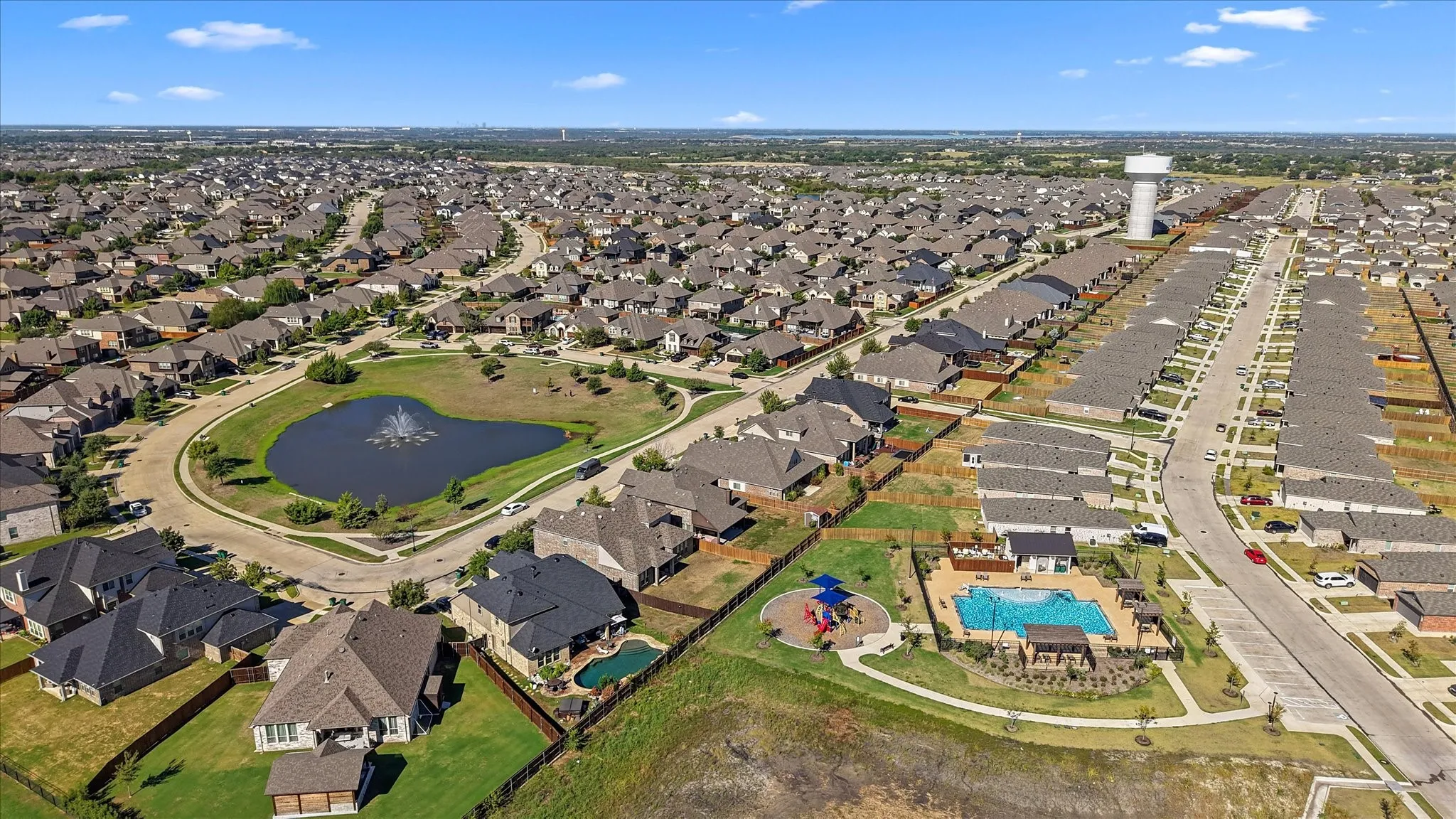 Expansive neighborhood with a central pond featuring a fountain, a community pool, and a dedicated play area