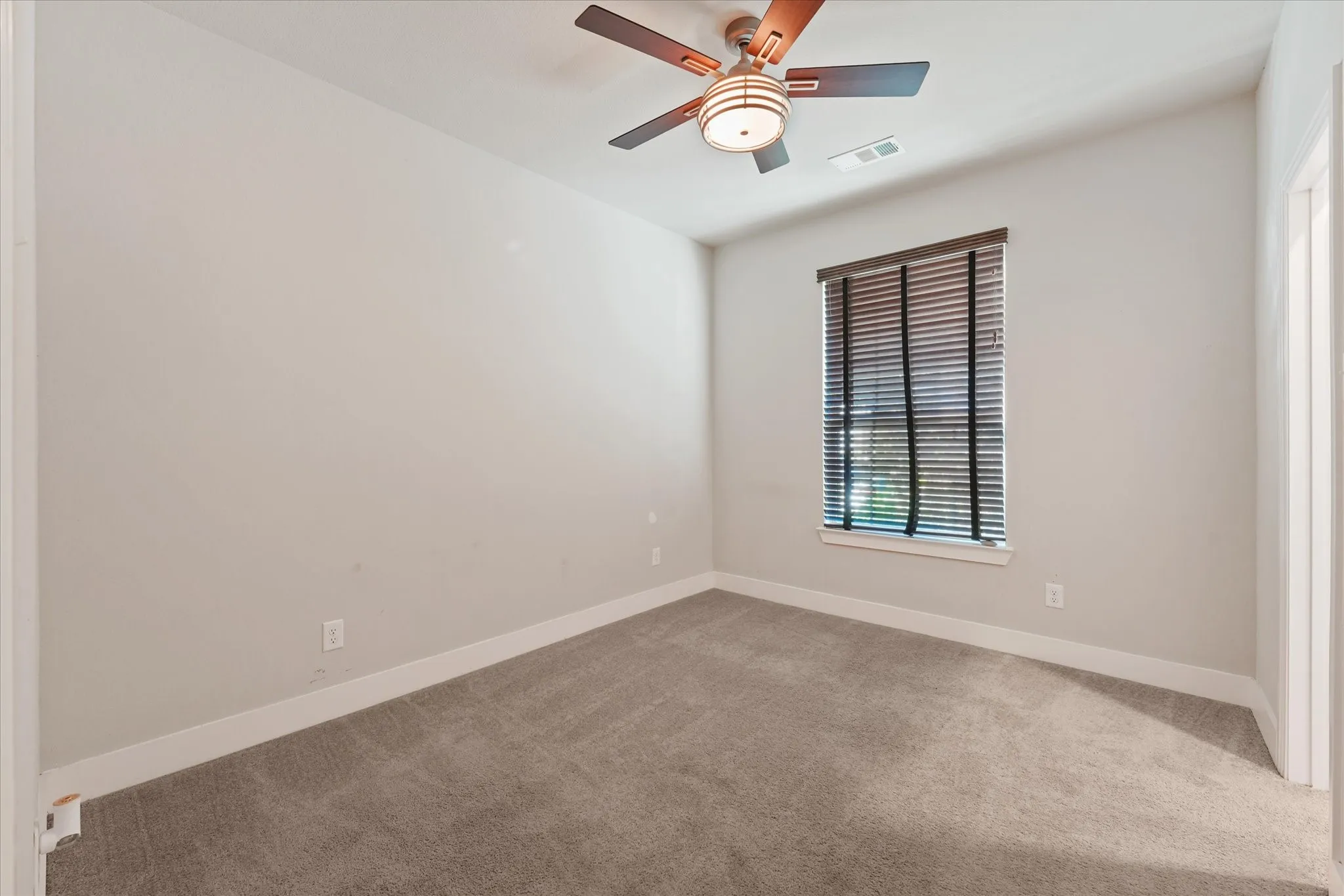 Neutral tone walls, ceiling fan, carpet flooring, window with blinds