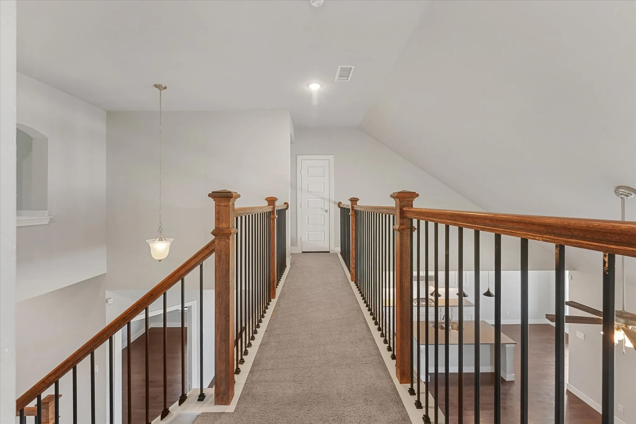 Upper-level hallway with carpet flooring and sloped ceiling