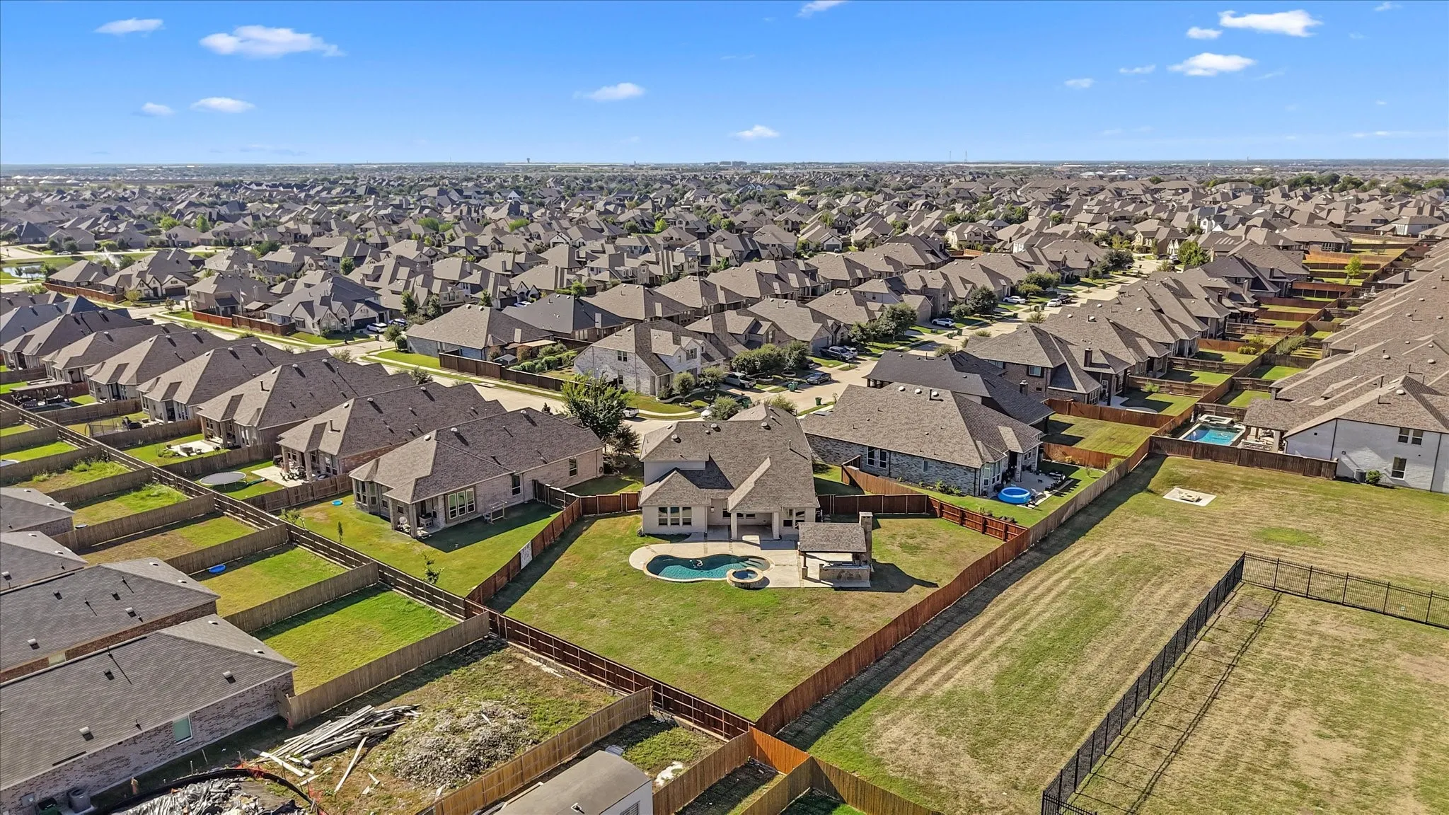 Spacious backyard featuring a fenced perimeter, inground pool with integrated spa, and an expansive lawn area