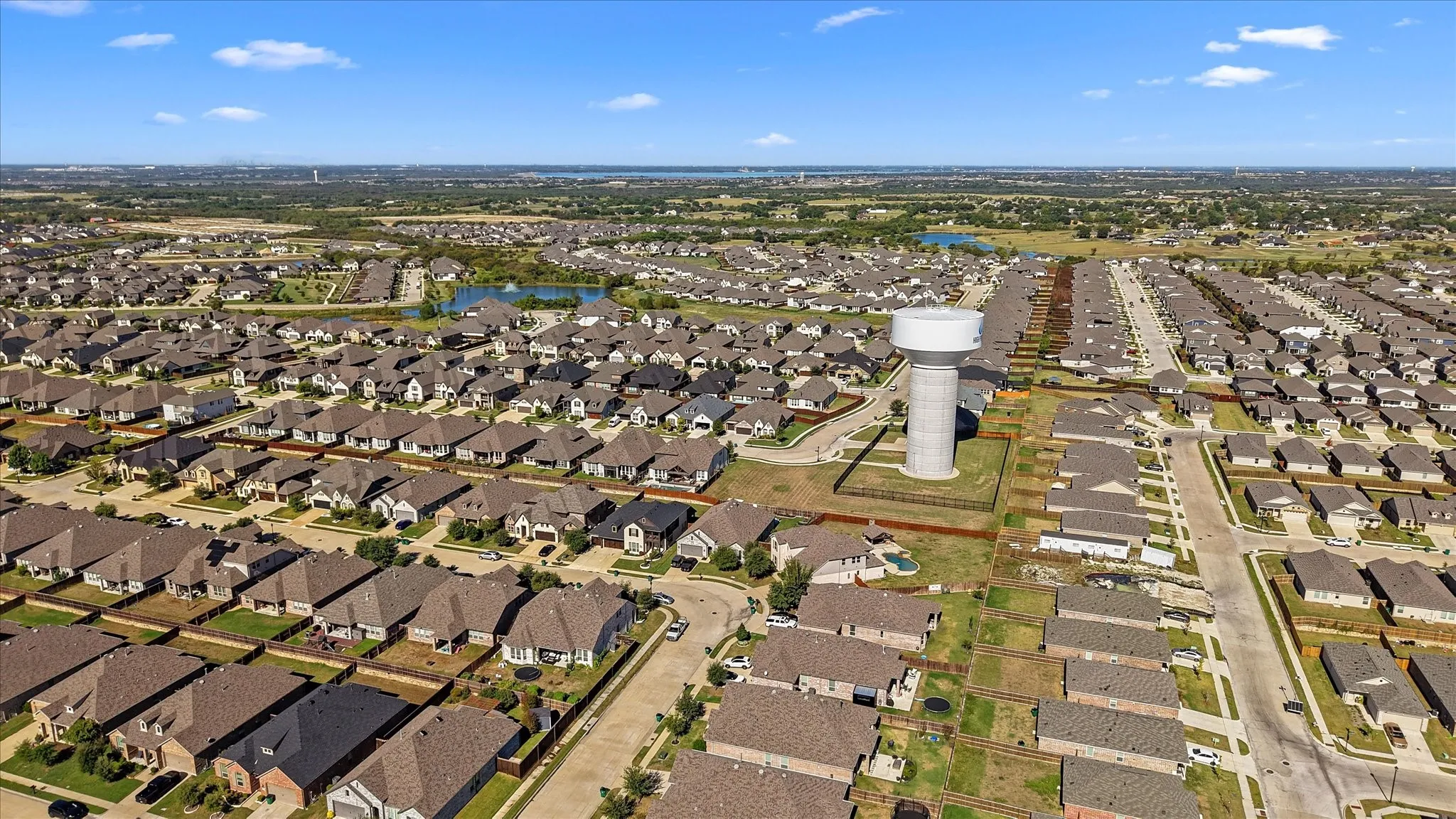 Expansive residential development featuring numerous single-family homes, paved streets, and a prominent water tower