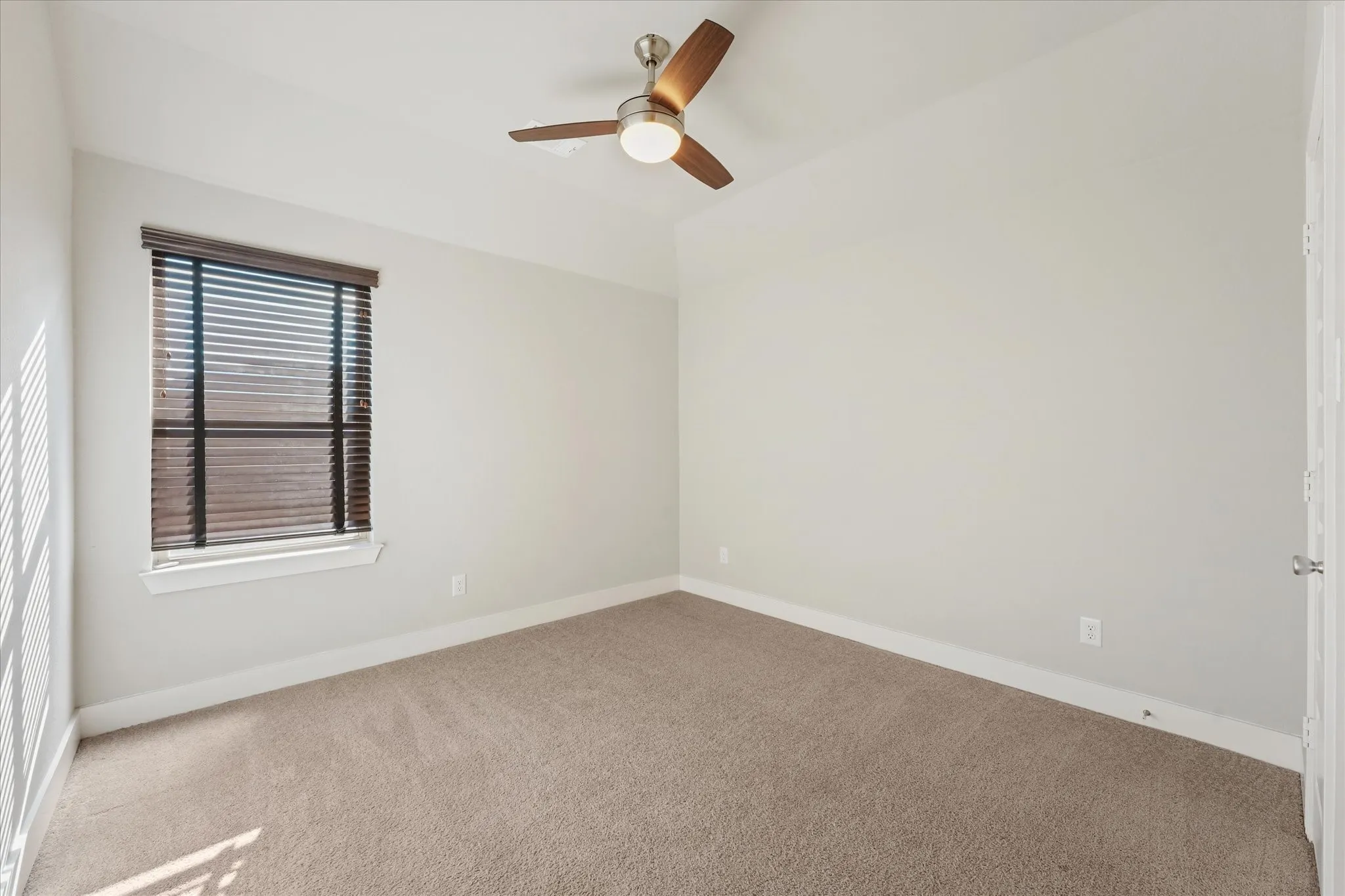 Recessed ceiling with an attached ceiling fan, neutral carpet flooring, and a single window with blinds
