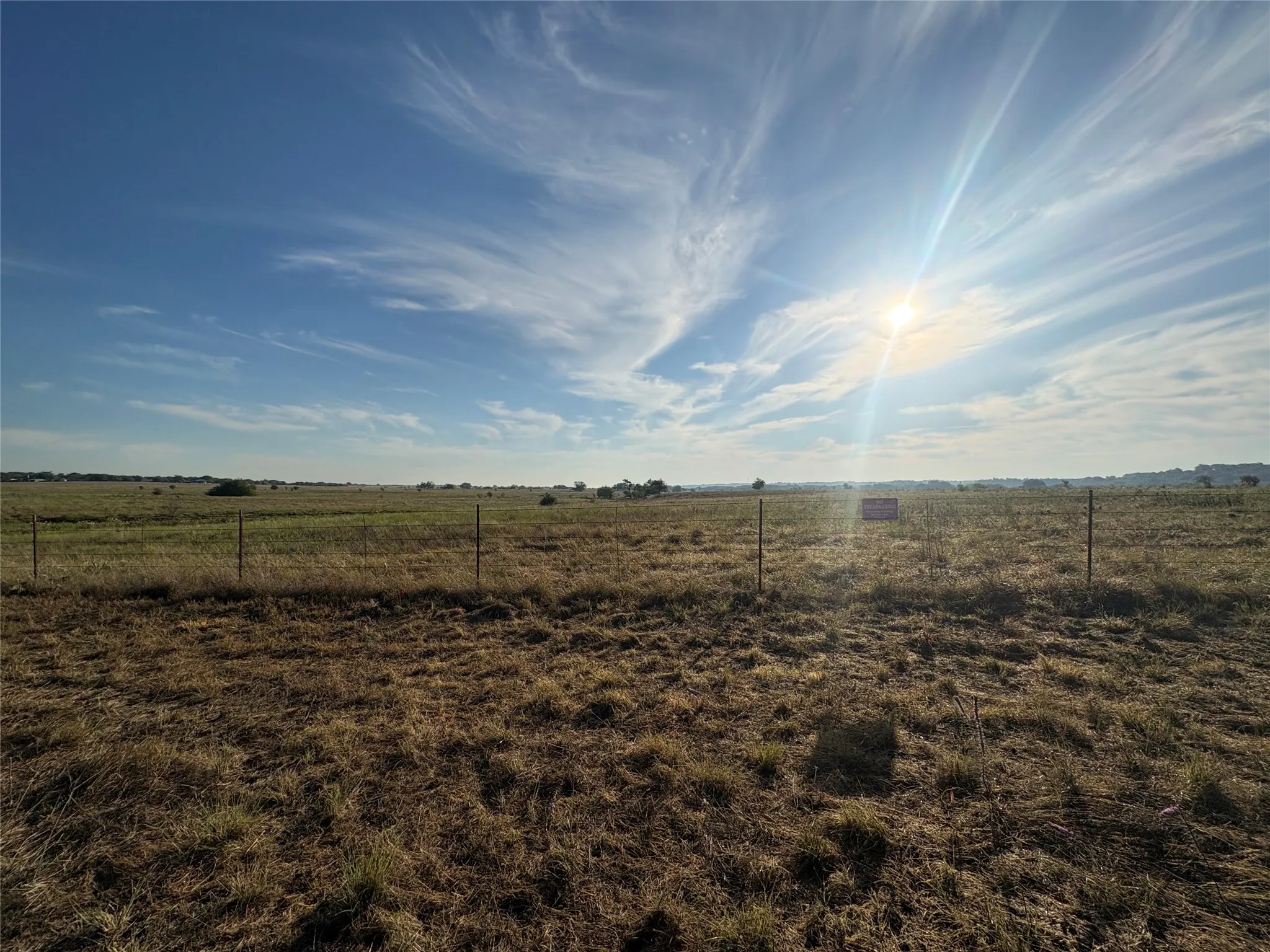 Expansive open land with a wire fence boundary and distant foliage