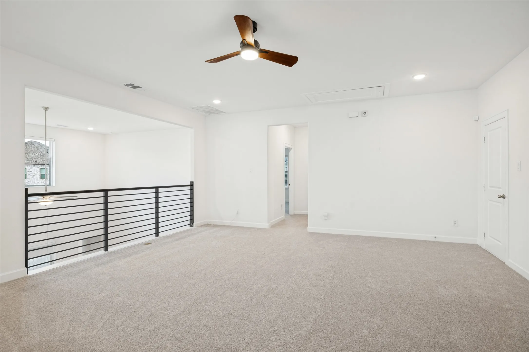 Spacious loft area featuring a wood-finish ceiling fan, recessed lighting, and neutral carpeting