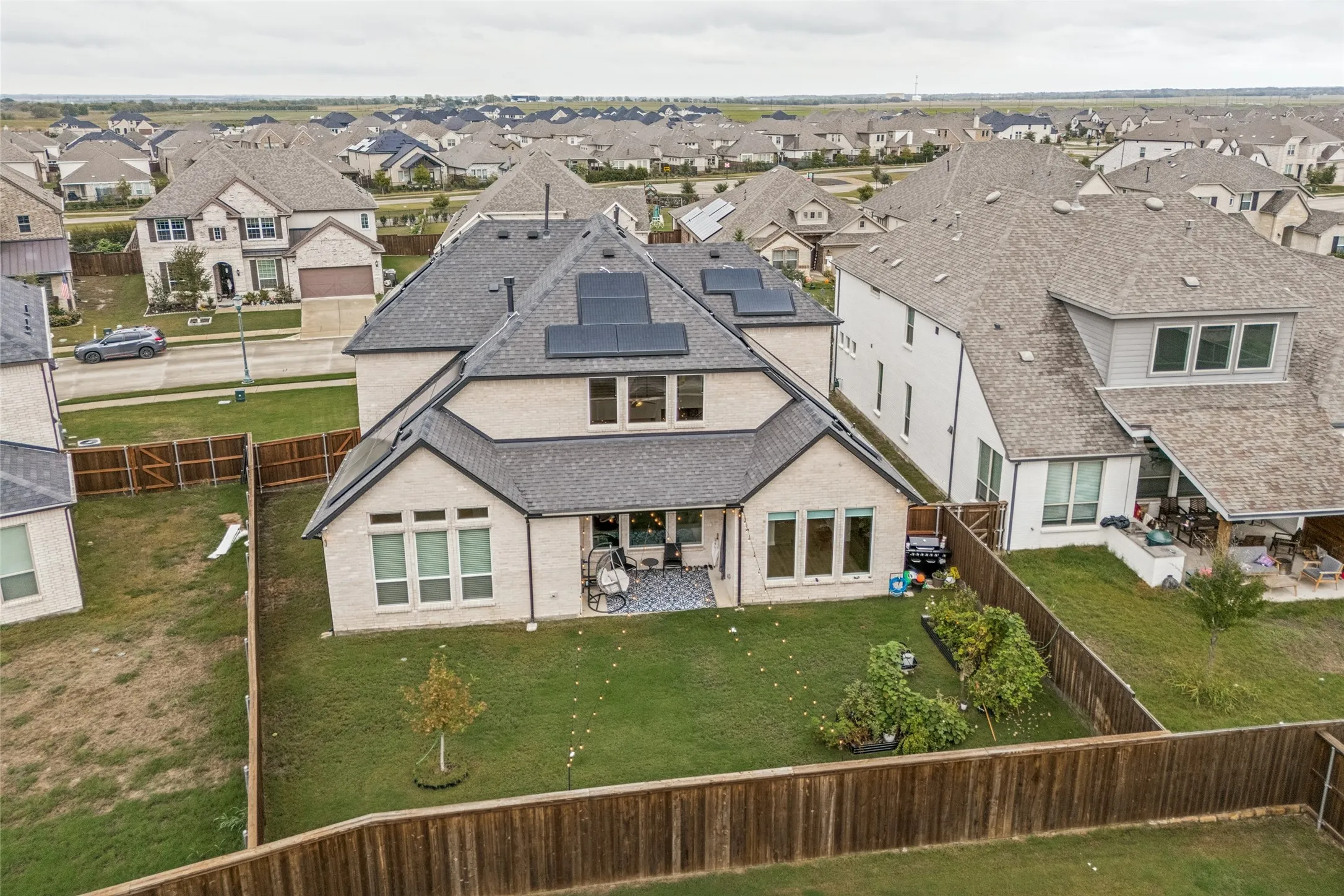 Expansive backyard with a manicured lawn, established landscaping, and a wood privacy fence