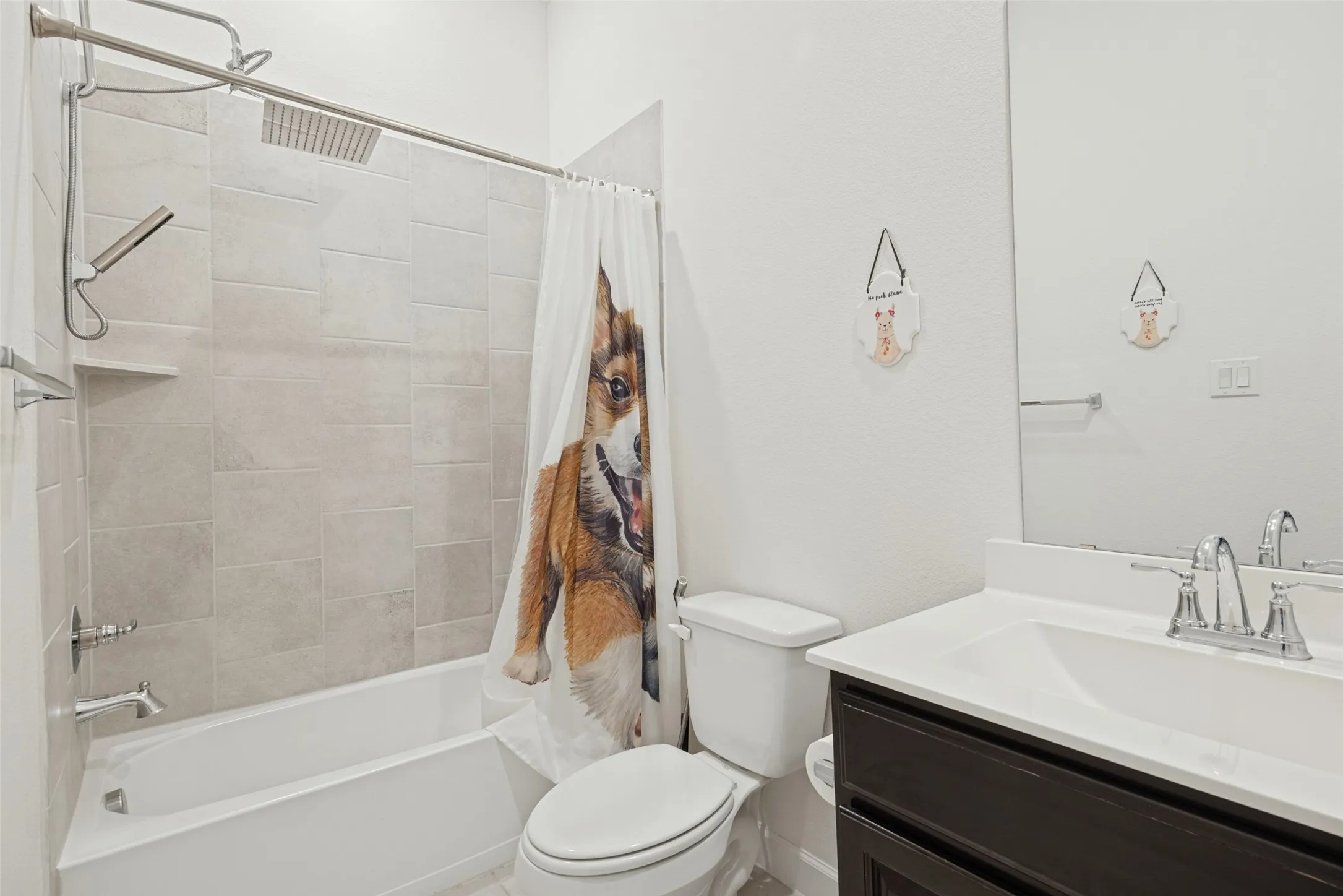 Bathtub with tiled surround, rain shower head, and wall-mounted handheld shower