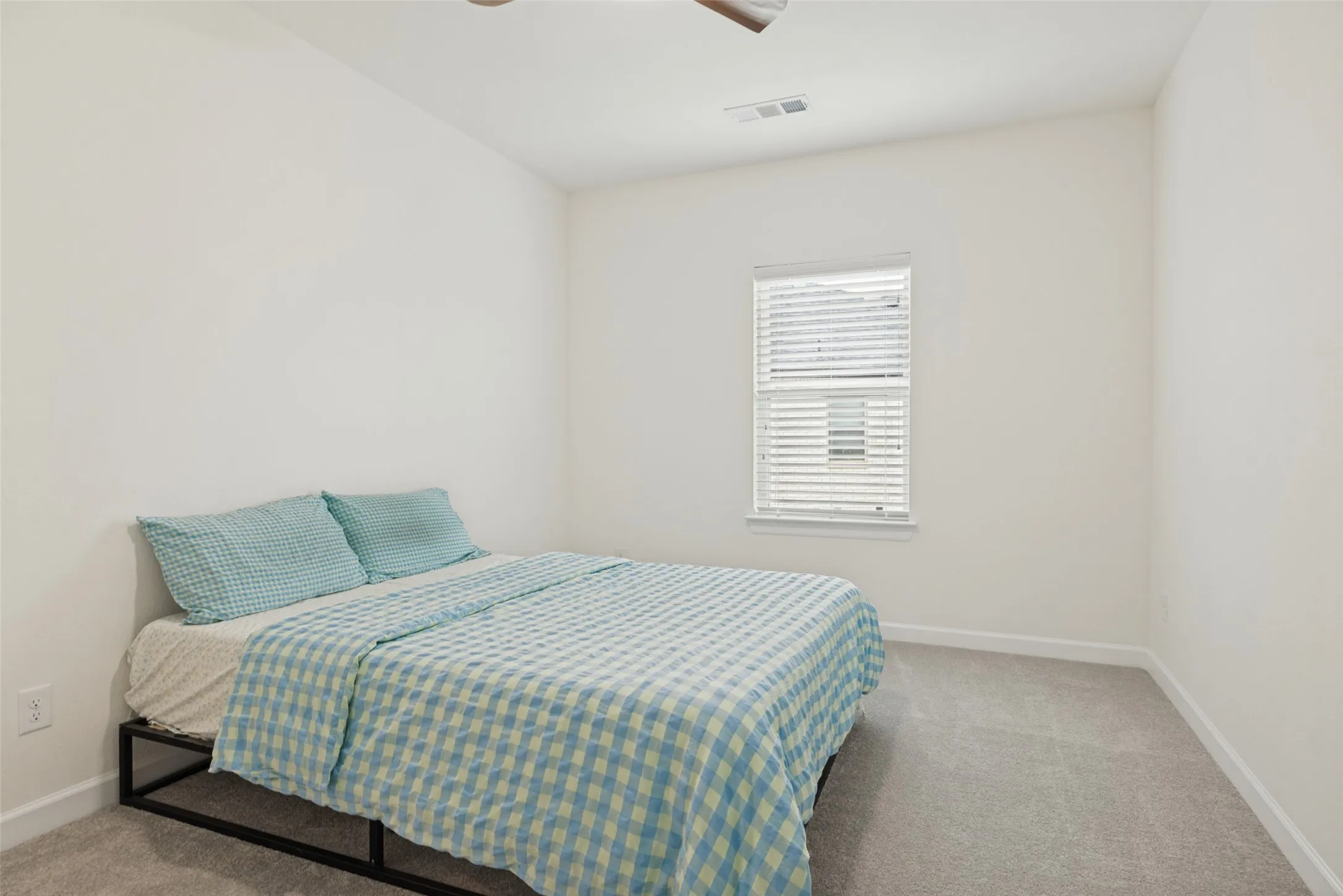 Neutral wall tones, gray carpeting, and a window with blinds