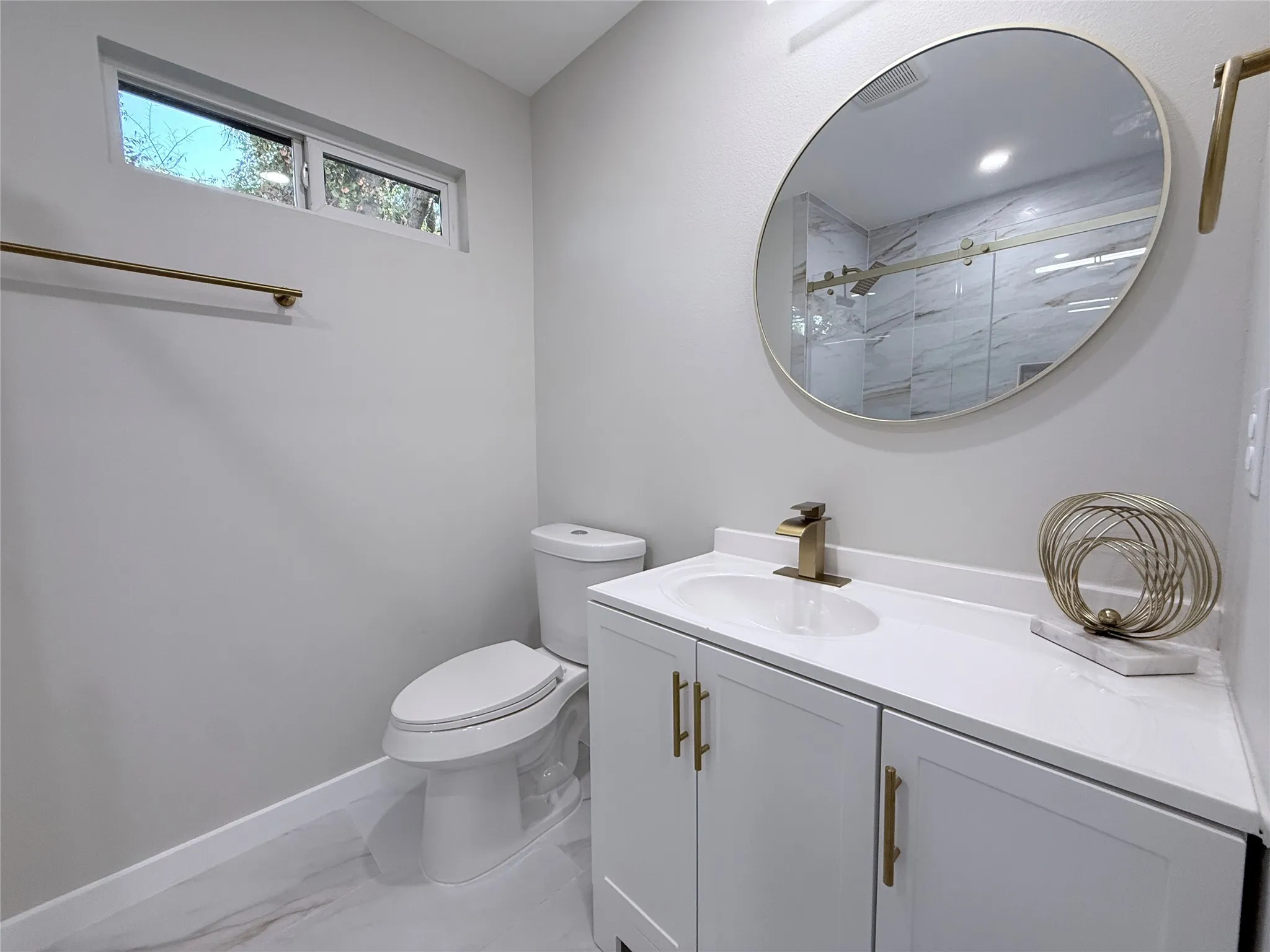 Vanity with white cabinetry, gold-tone hardware, and an integrated sink