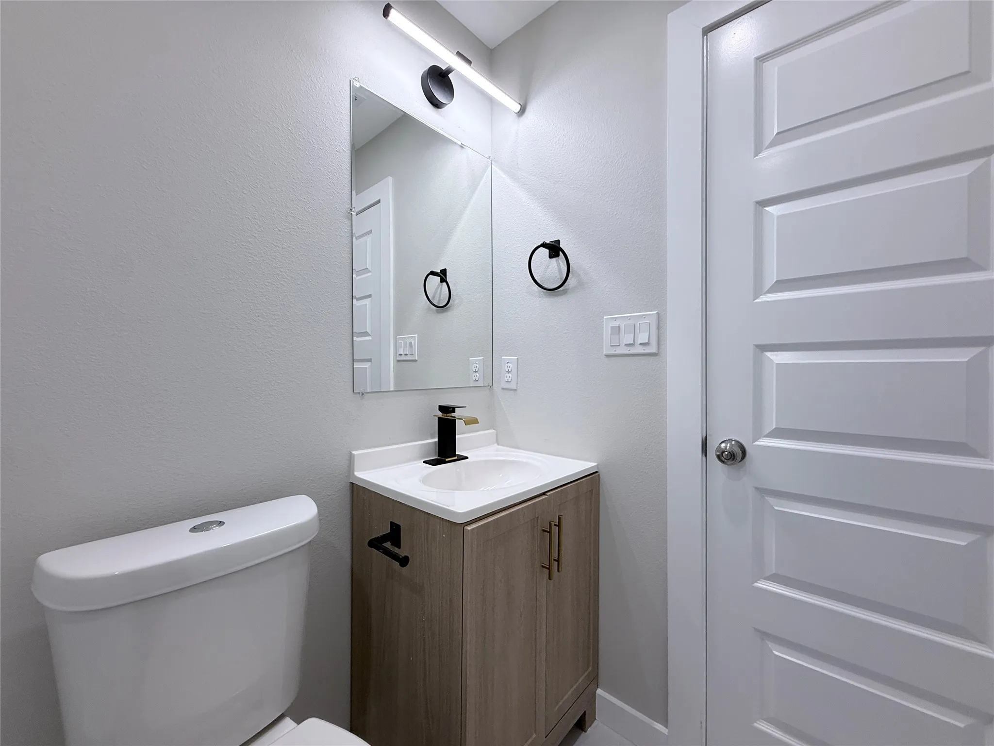 Vanity with wood-finish cabinetry, white countertop, and integrated sink