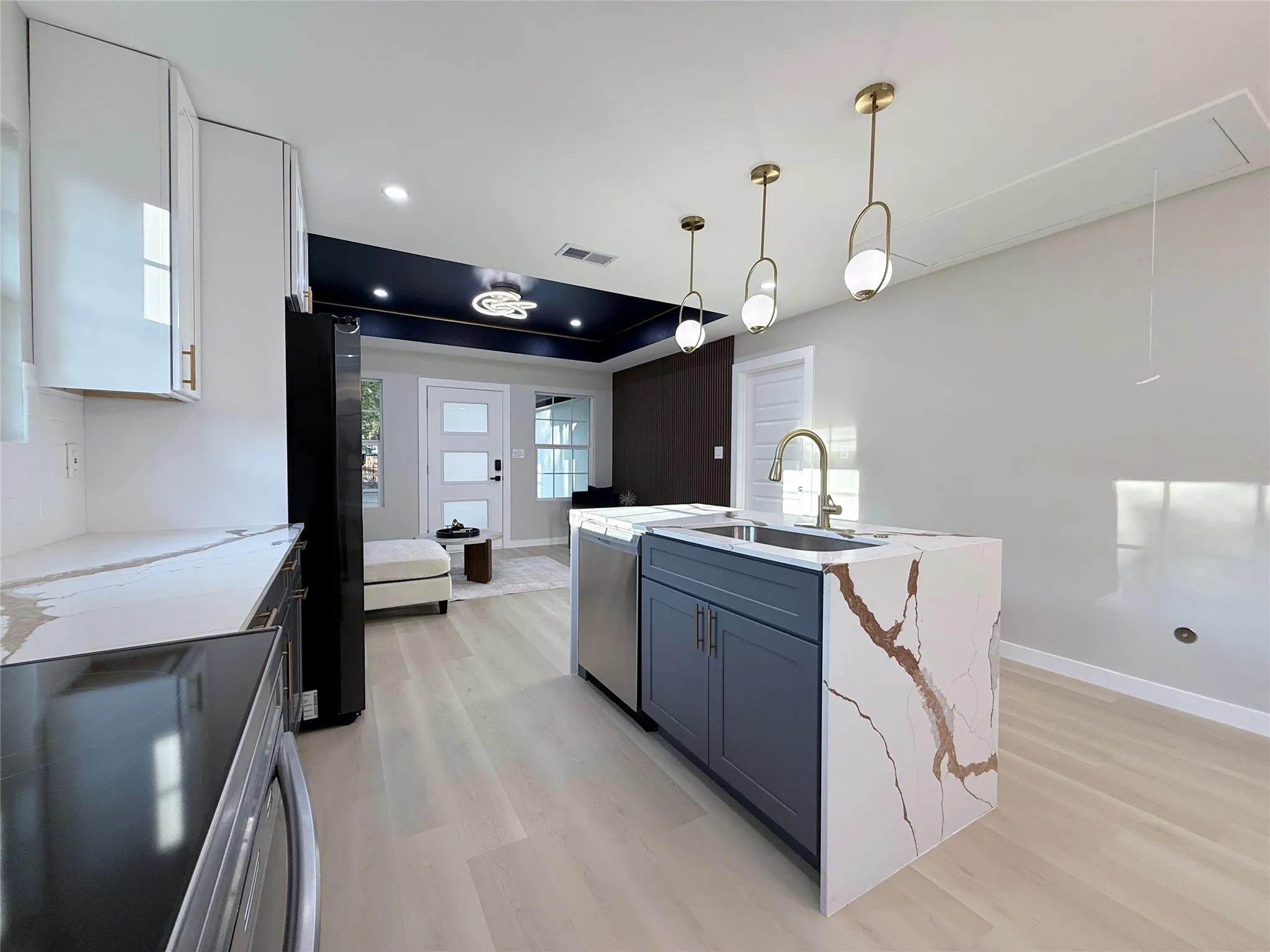 Kitchen island with a waterfall-edge countertop, undermount sink, and brass-finish faucet