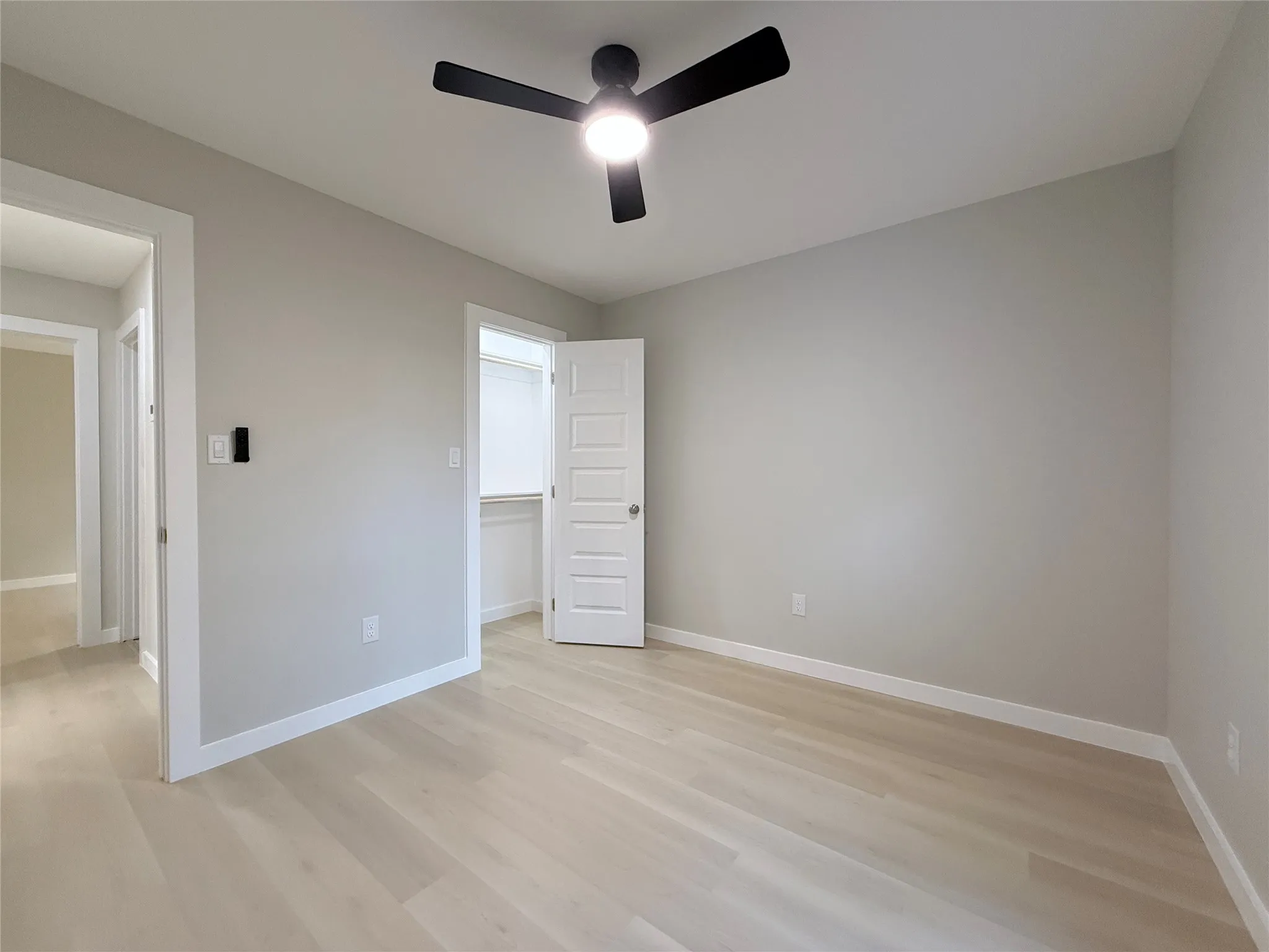 Light-toned wood-finish flooring, recessed lighting, ceiling fan with integrated light, and a walk-in closet with built-in shelving